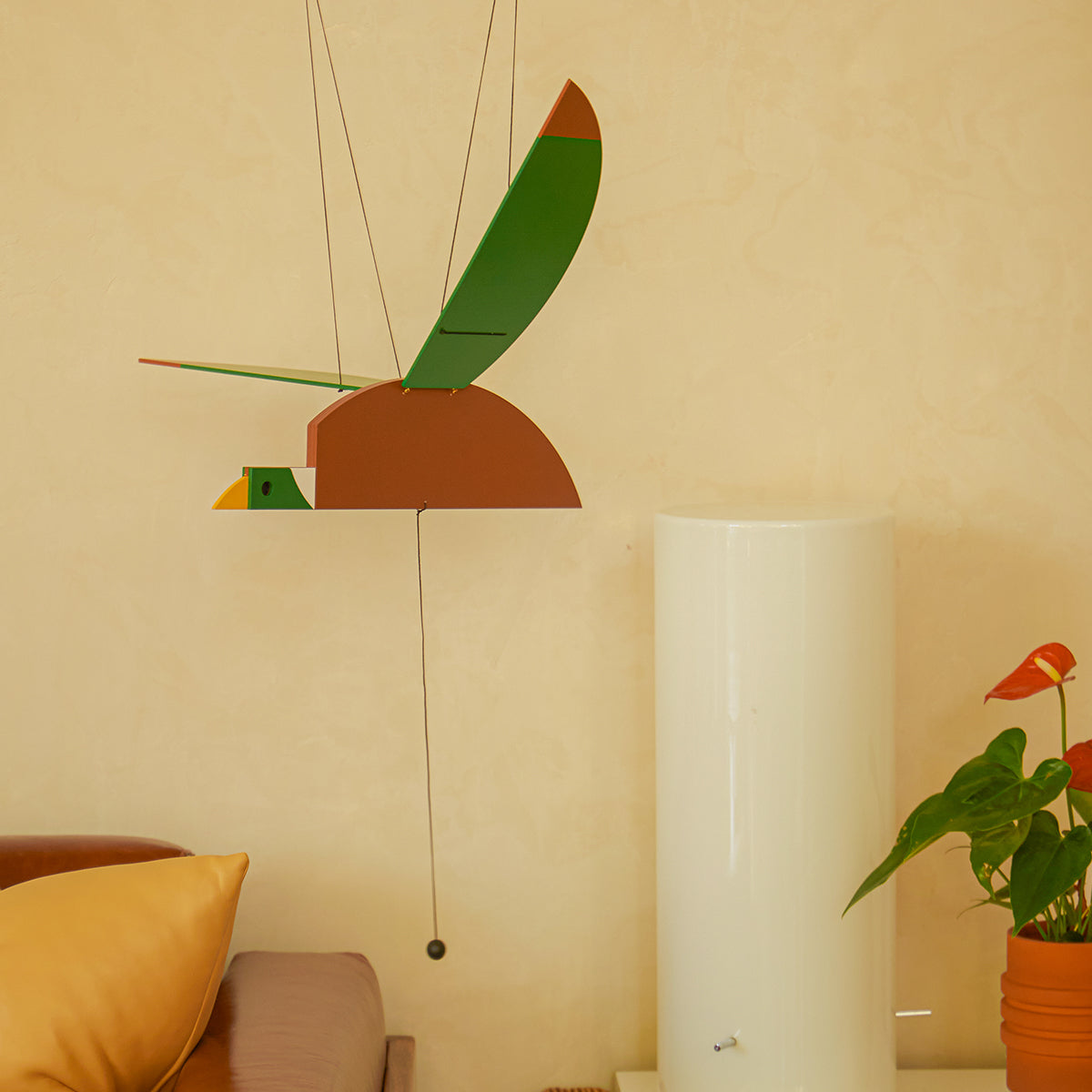 Areaware Duck Mobile flying above bed near red flowering plant in bedroom scene