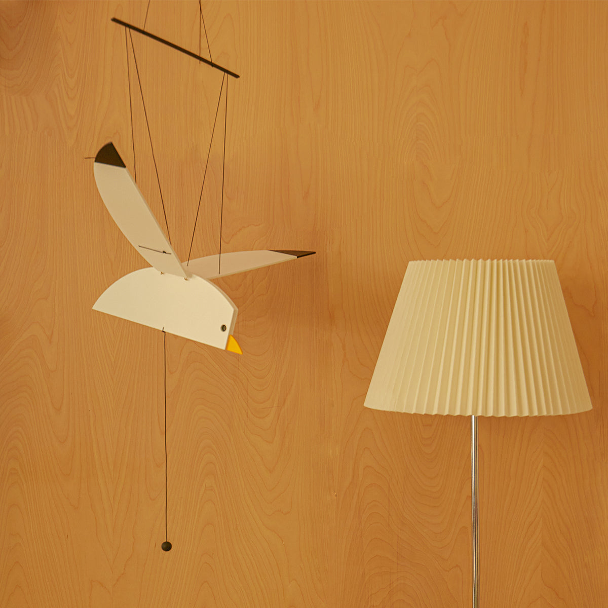 Areaware Seagull Mobile flying next to white lamp in front of wood wall