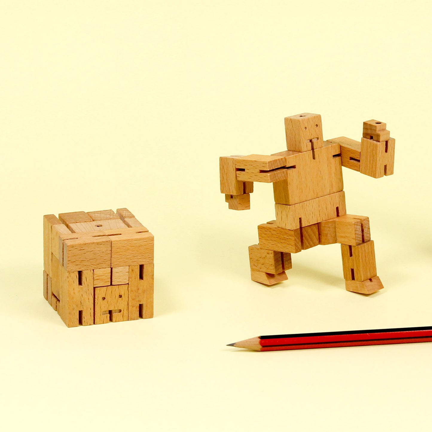 Showing its two form, the cube and the robot from Areaware Cubebot Micro wooden toy robot - natural beech-wood figure with elastic joints, folds into a 1.5-inch cube and poses in multiple positions; compact, durable, and suitable for ages 4+.