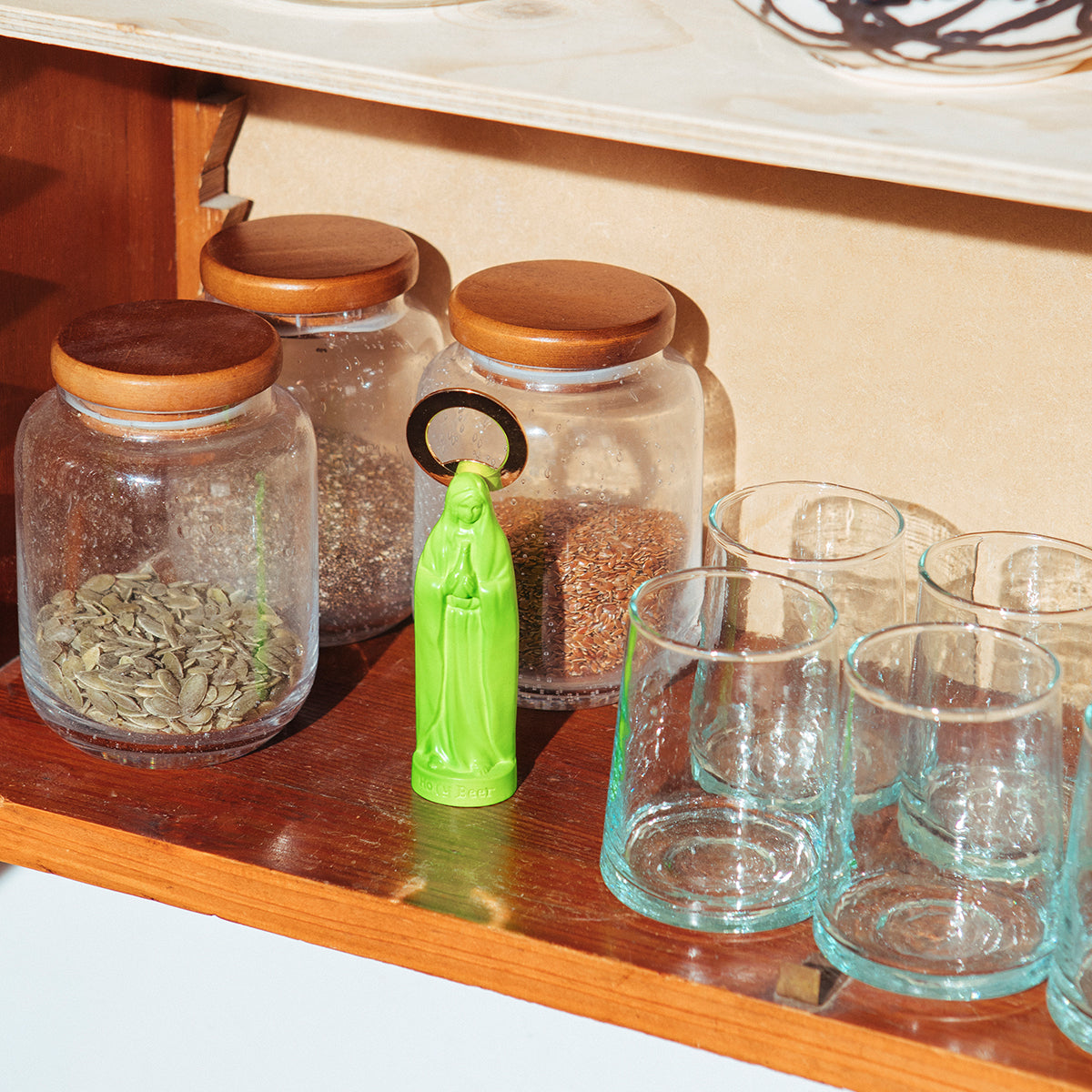 Doiy green holy beer bottle opener on wooden kitchen shelf next to storage jars