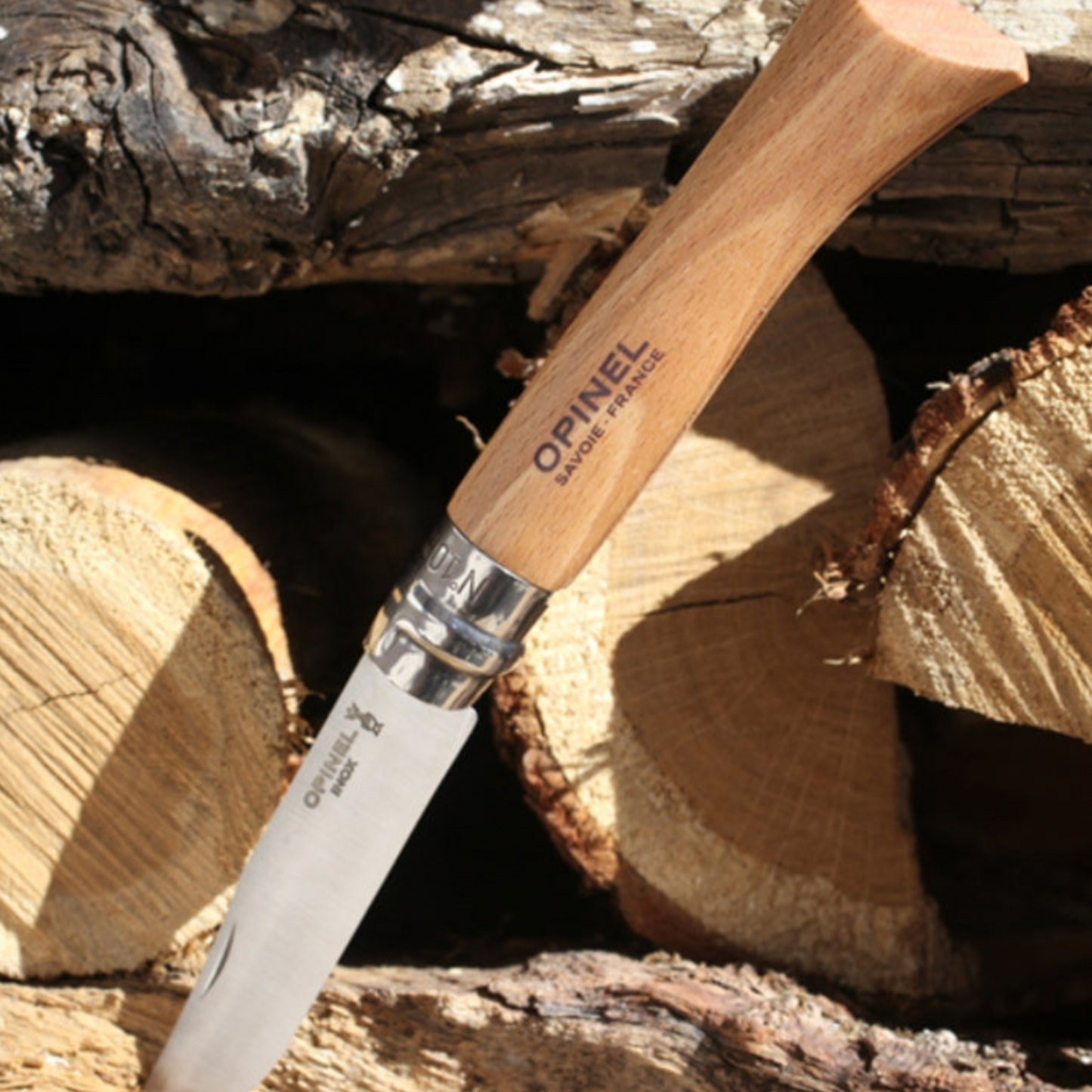 One of Opinel folding knife 10pc Set outdoors with logs of wood