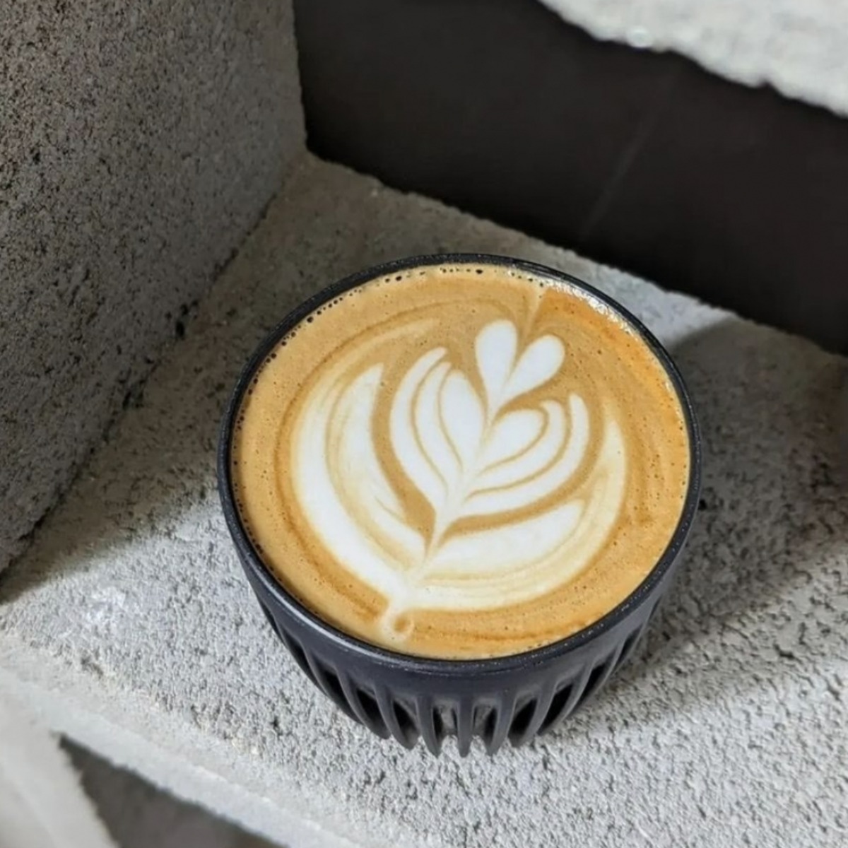 HuskeeCup 6oz with Lid Charcoal out of on display on cinder blocks with coffee in the cup