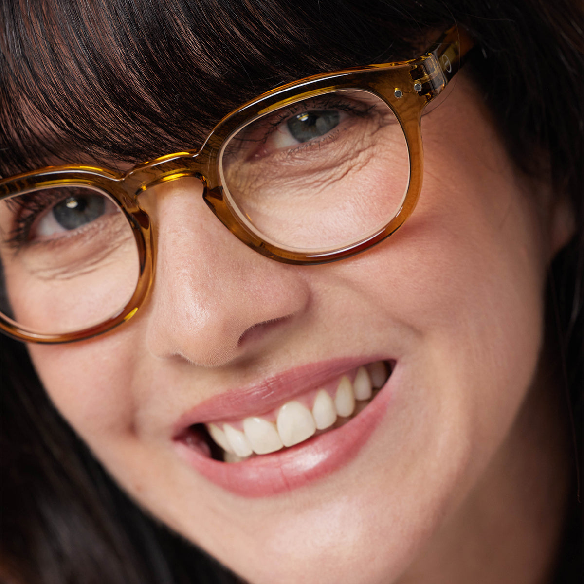 Close up of woman wearing Izipizi shape c golden green reading glasses