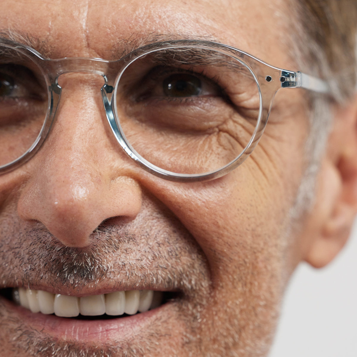 Close up of man wearing Izipizi shape d frozen blue reading glasses on white background with grey hair and navy tshirt