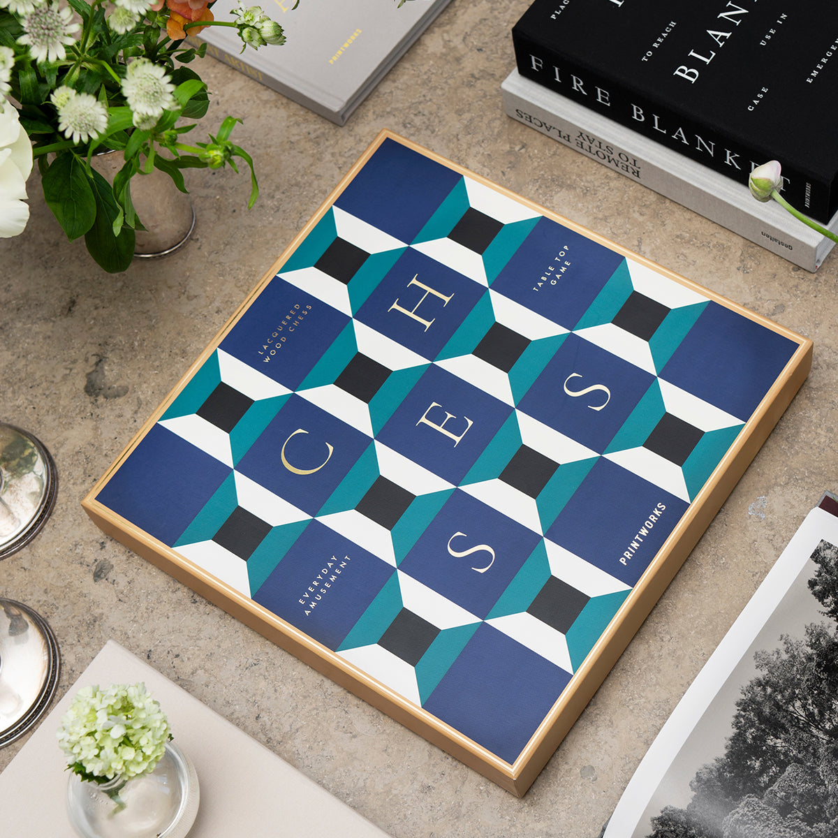 Printworks classic chess game lacquered athena on an angle on marble table with flowers and books