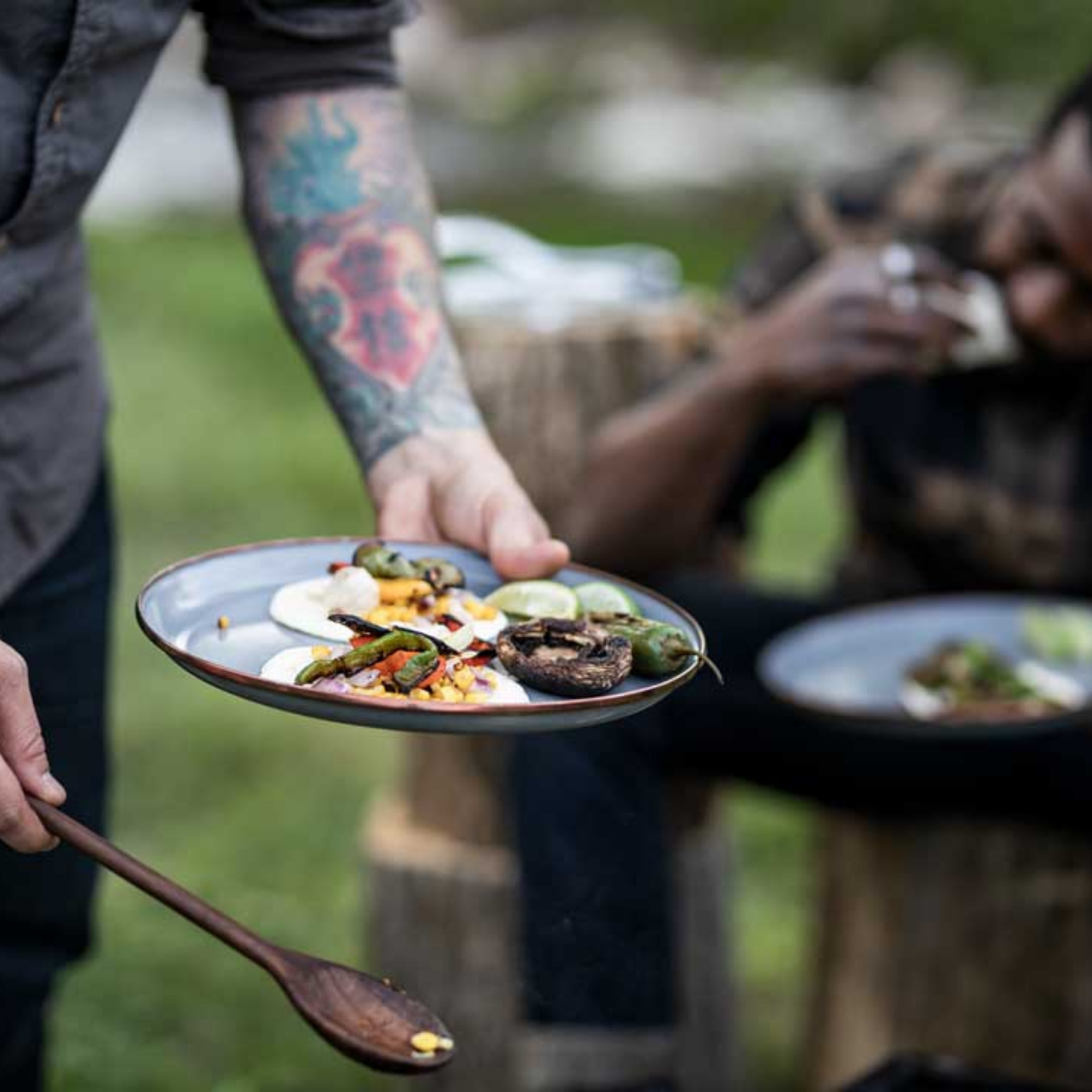 Man holding Barebones enamel plate deep slate and serving food.