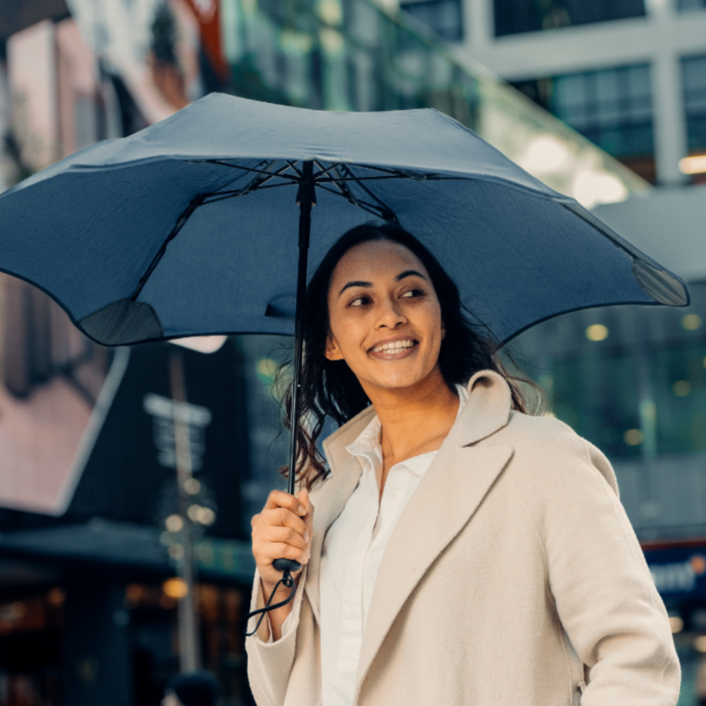 Woman holding Blunt navy metro umbrella walking through the city