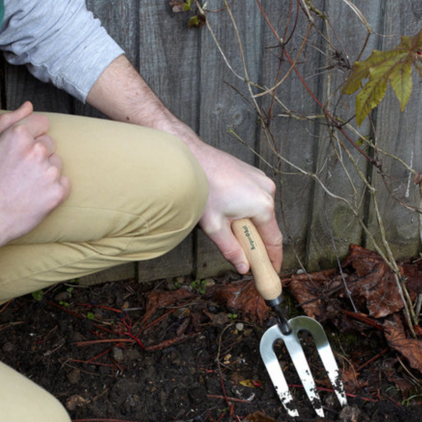 Man using Burgon & Ball stainless steel hand fork in garden