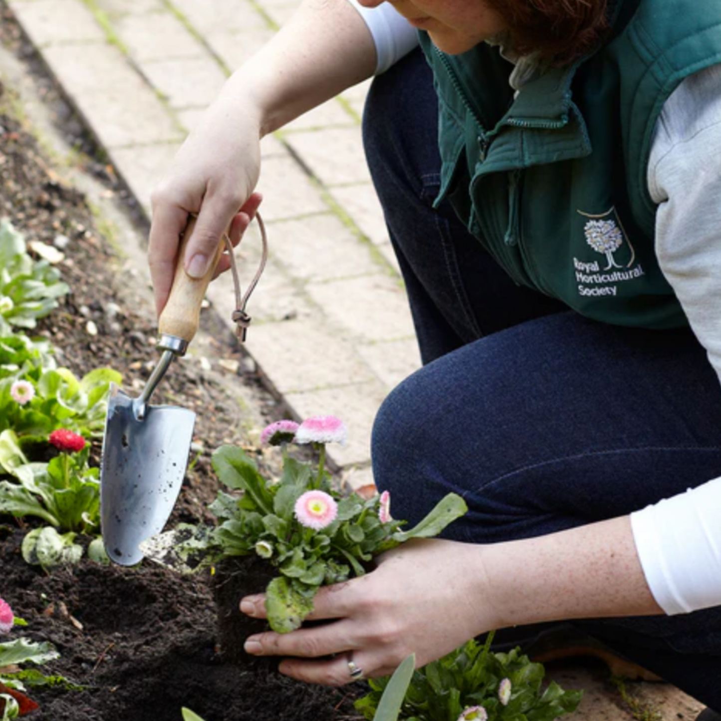 Woman using Burgon & Ball stainless steel hand trowel in garden