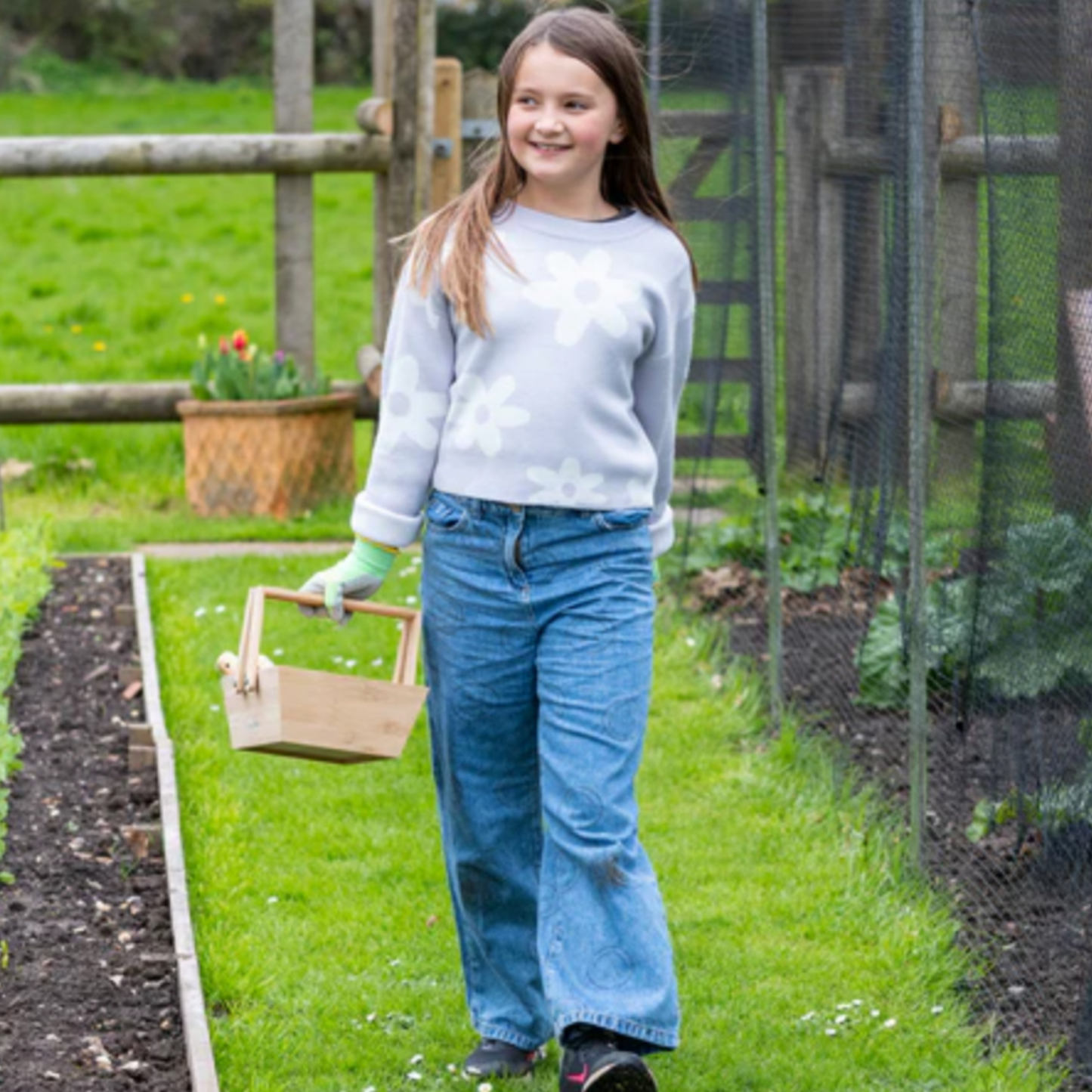 Young girl walking with Burgon & Ball kids wooden harvesting basket in vegetable patch