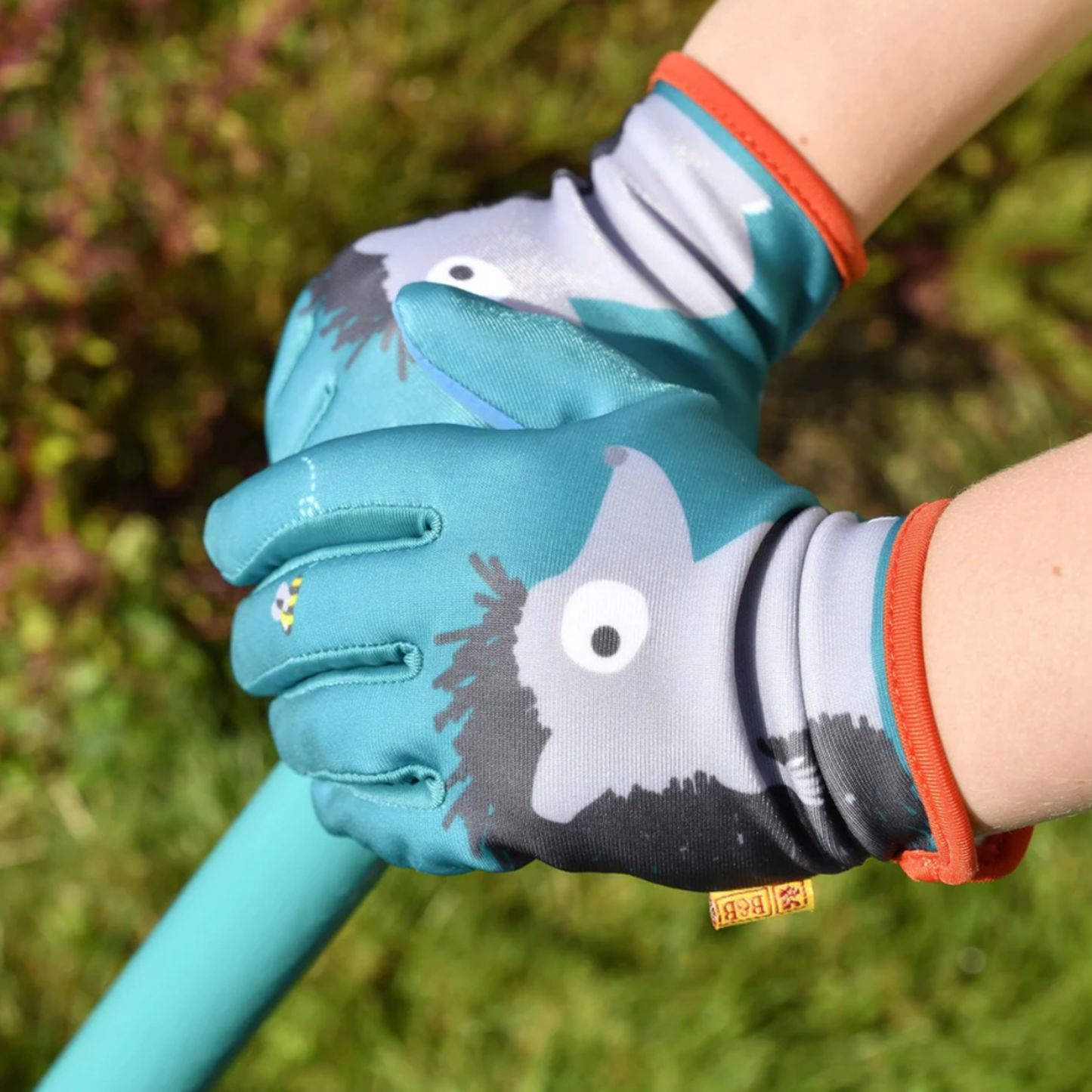 Little kid wearing Burgon & Ball kids gardening gloves hedgehog outside