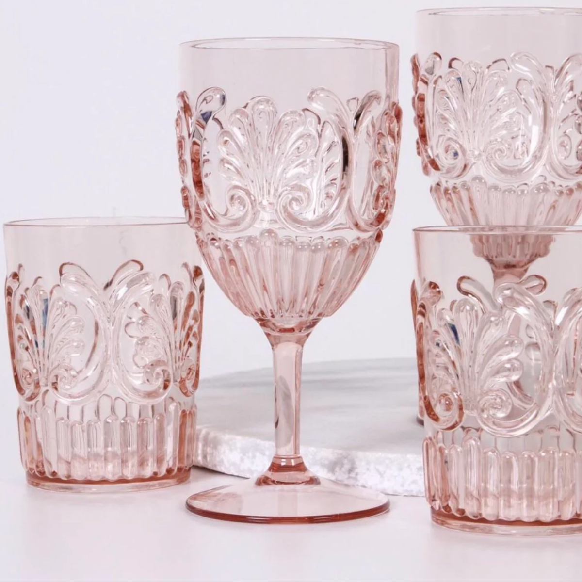 Collection of plae pink acrylic glassware on display and marble plate