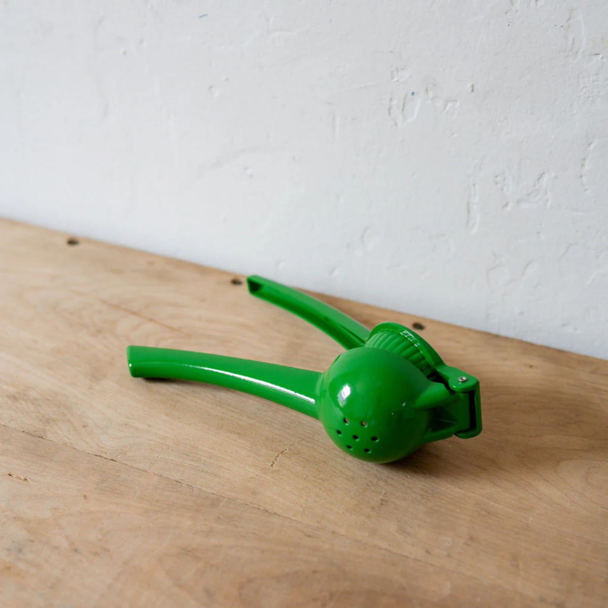 Green metal Lime squeezer on side half opened on wooden table back view