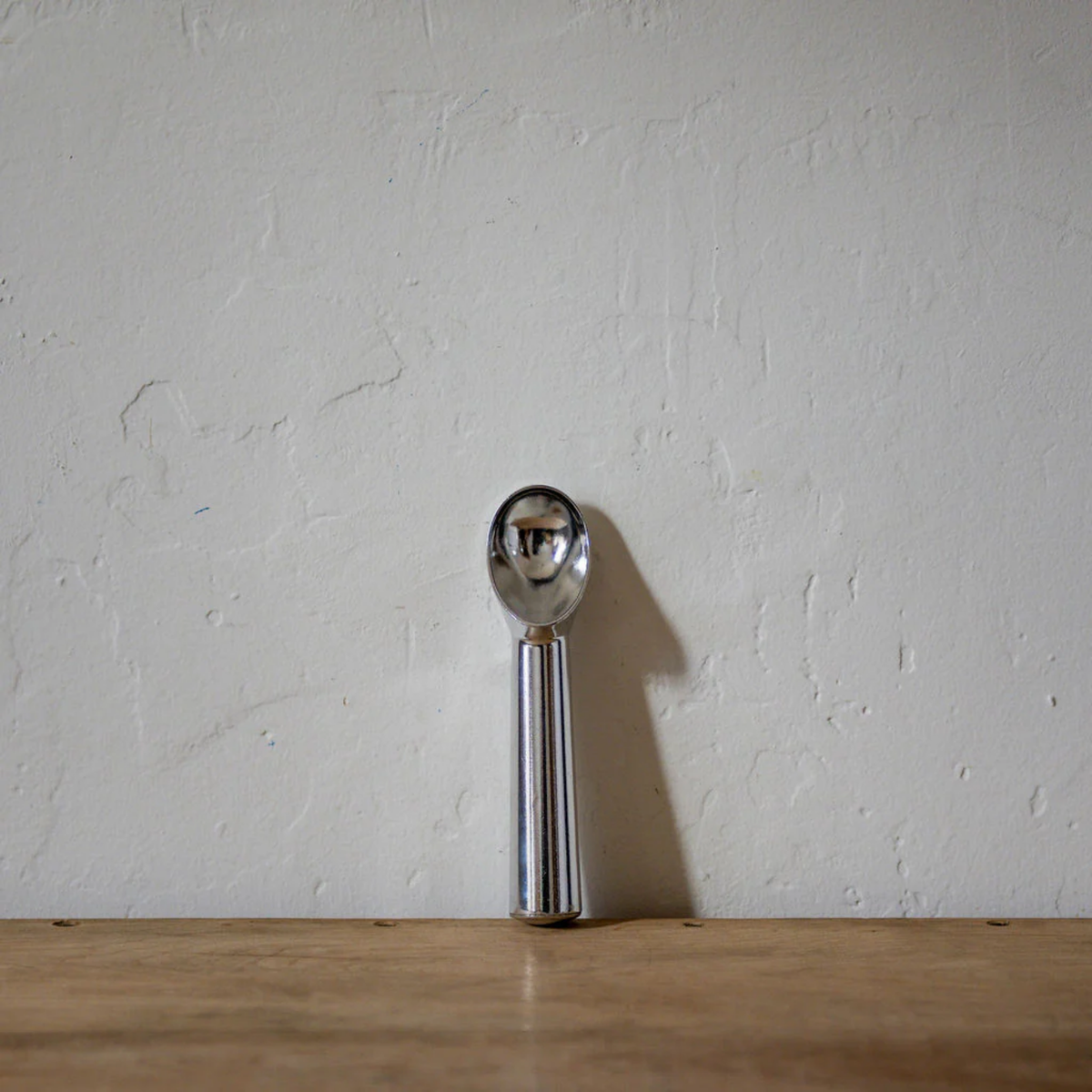 Aliminium ice cream scoop front view on wooden countertop