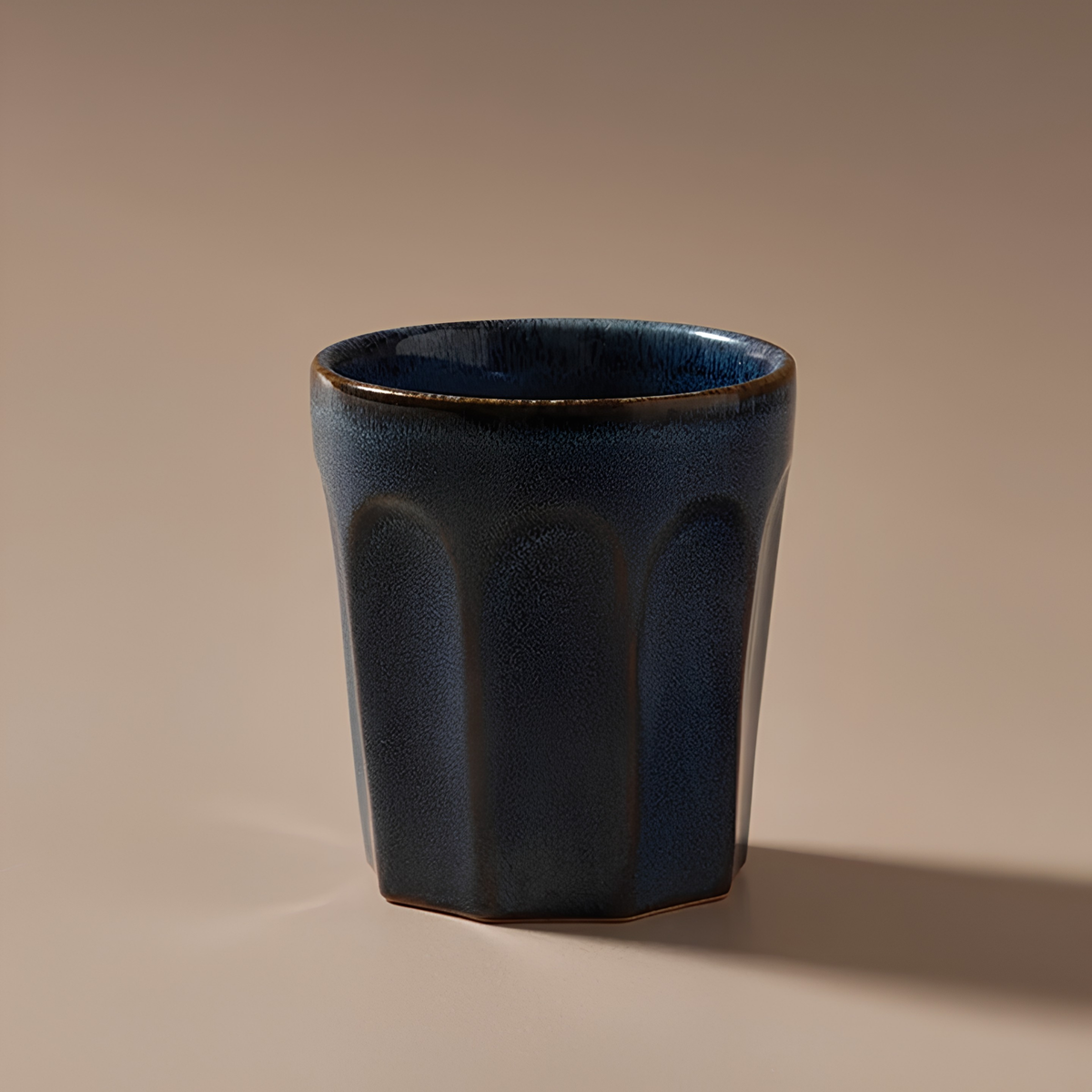Front view with a background of Fathom Latte Cup Navy stoneware that is handcrafted with reactive glazes of earthly hues finish.