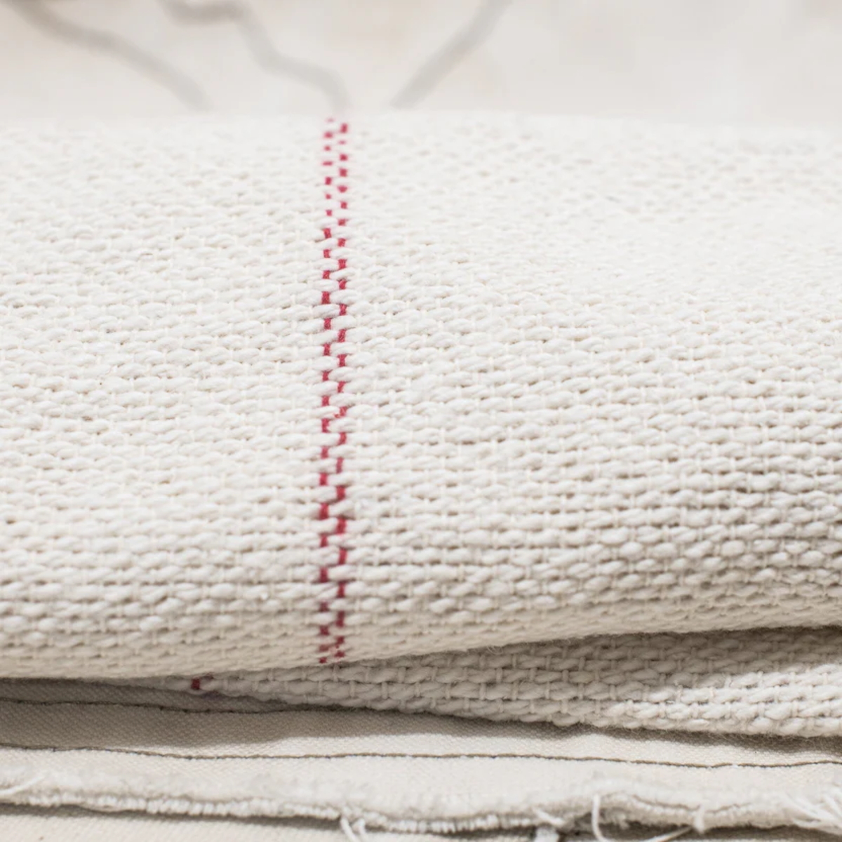 Close up view of the stripe of the Fathom Red Stripe Selvedge Cloth, durable all-rounder with selvedge ends for versatile household and kitchen use.