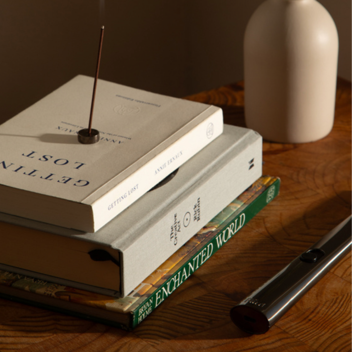 Flint rechargeable gunmetal lighter on wooden coffee table next to books and incense