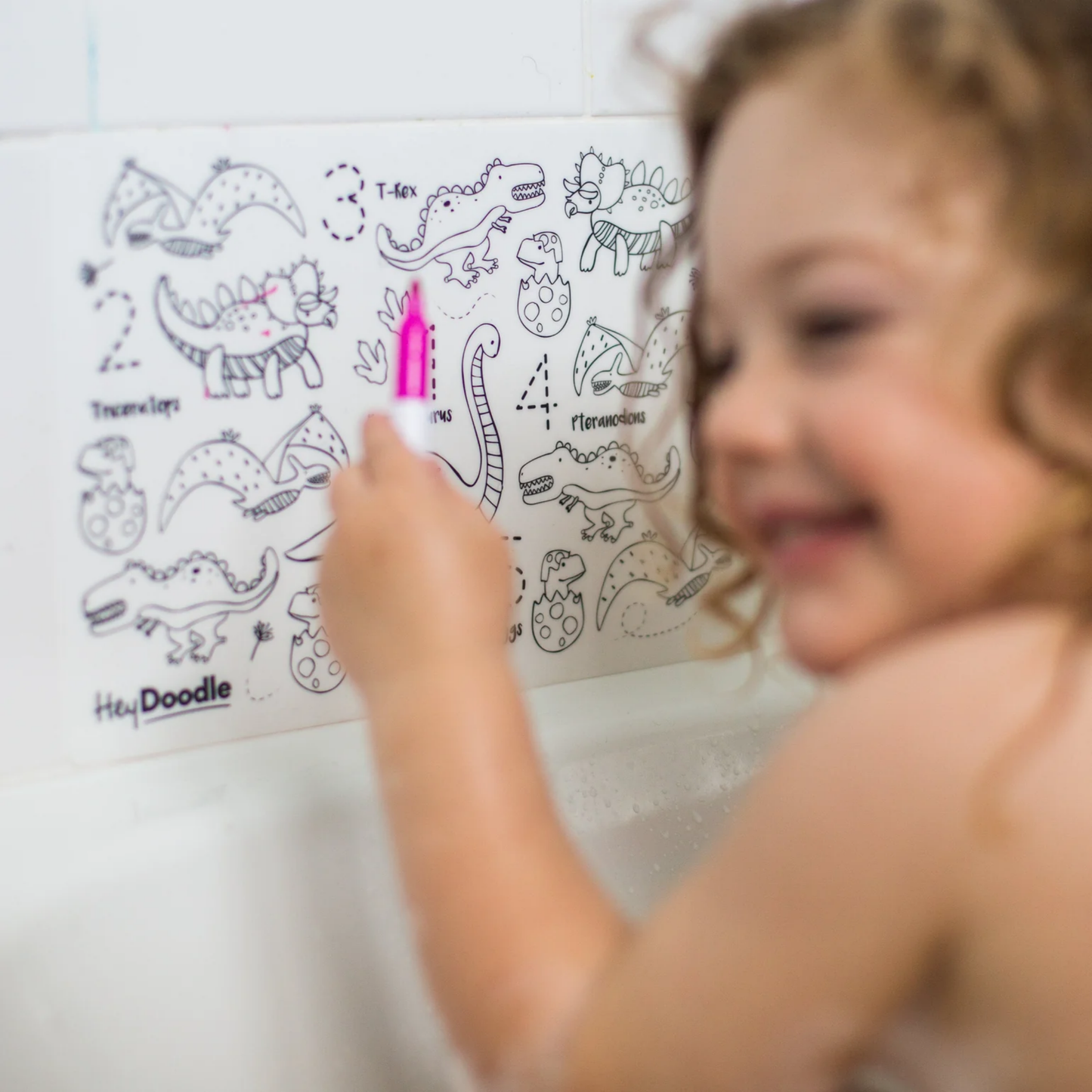 Little girl drawing with Hey Doodle mat in bathtub