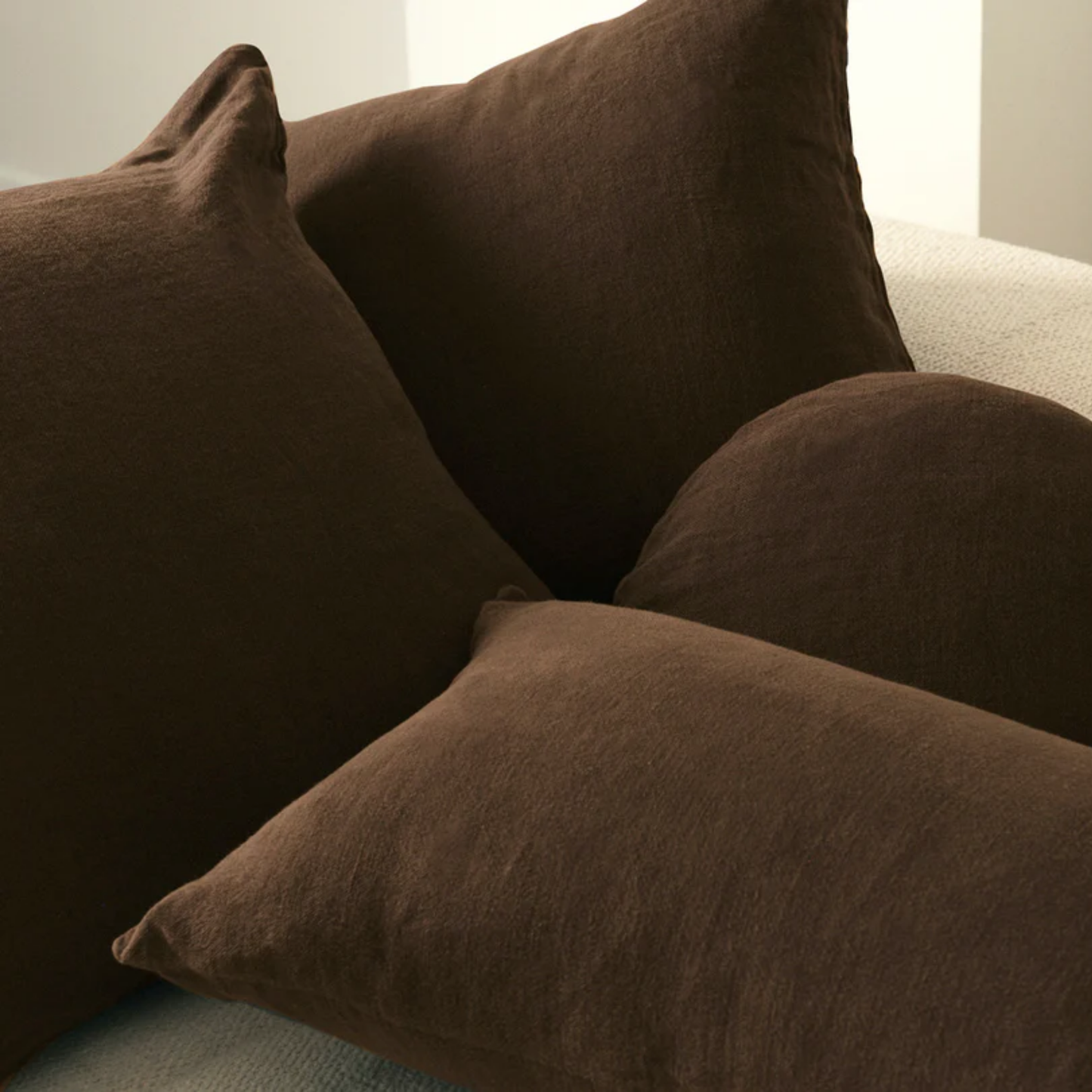 Hommey linen cushion chocolate on display on couch with linen blush range