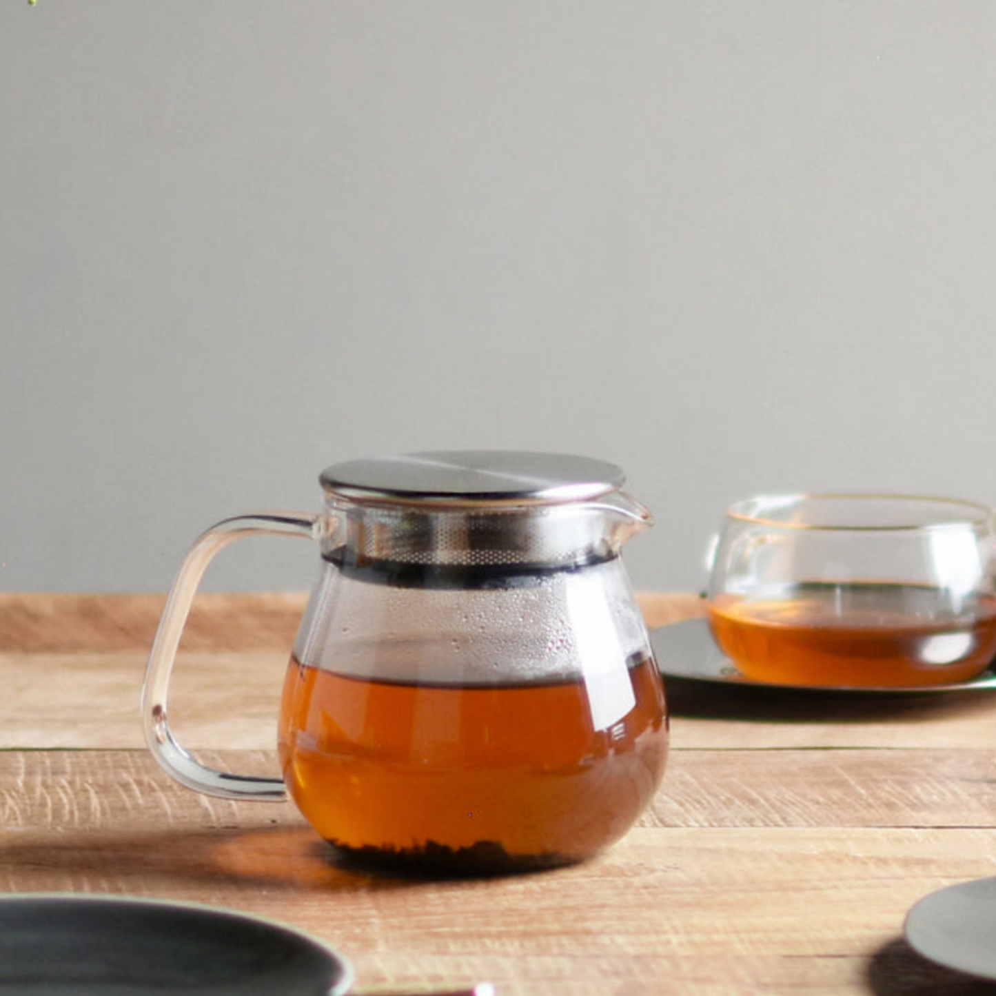 Stylish Kinto glass and stainless steel Unitea One Touch Teapot 460ml filled with tea on display on wooden table with Kinto glassware varieties