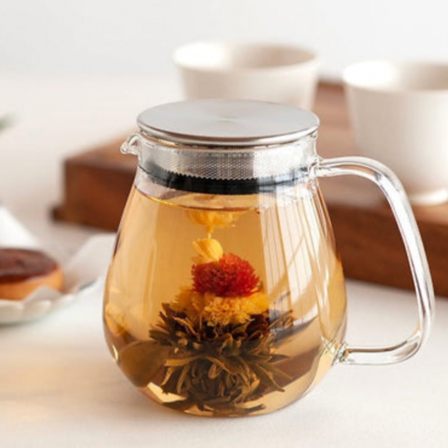 Stylish Kinto glass and stainless steel Unitea One Touch Teapot 720ml full with tea diapled on wooden coffee table with mugs in the background