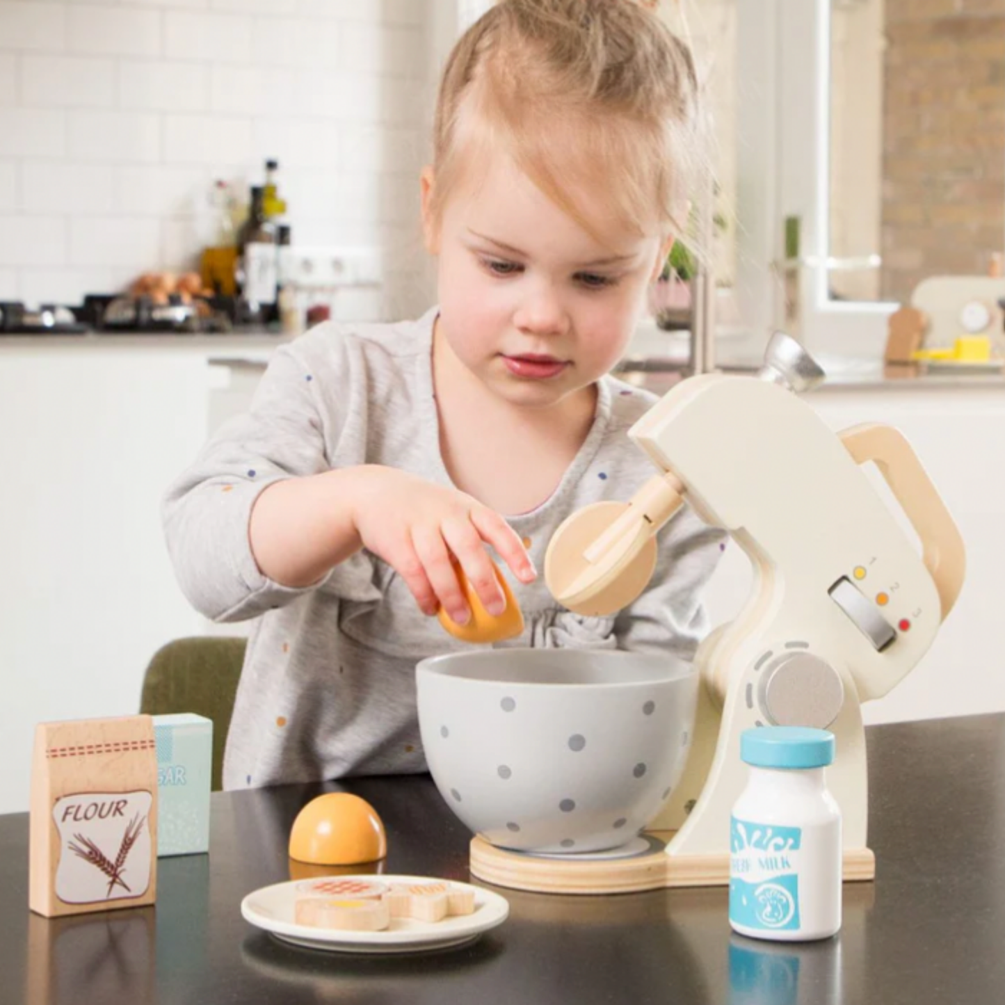 Little girl playing with New Classic Toys wooden baking set in kitchen