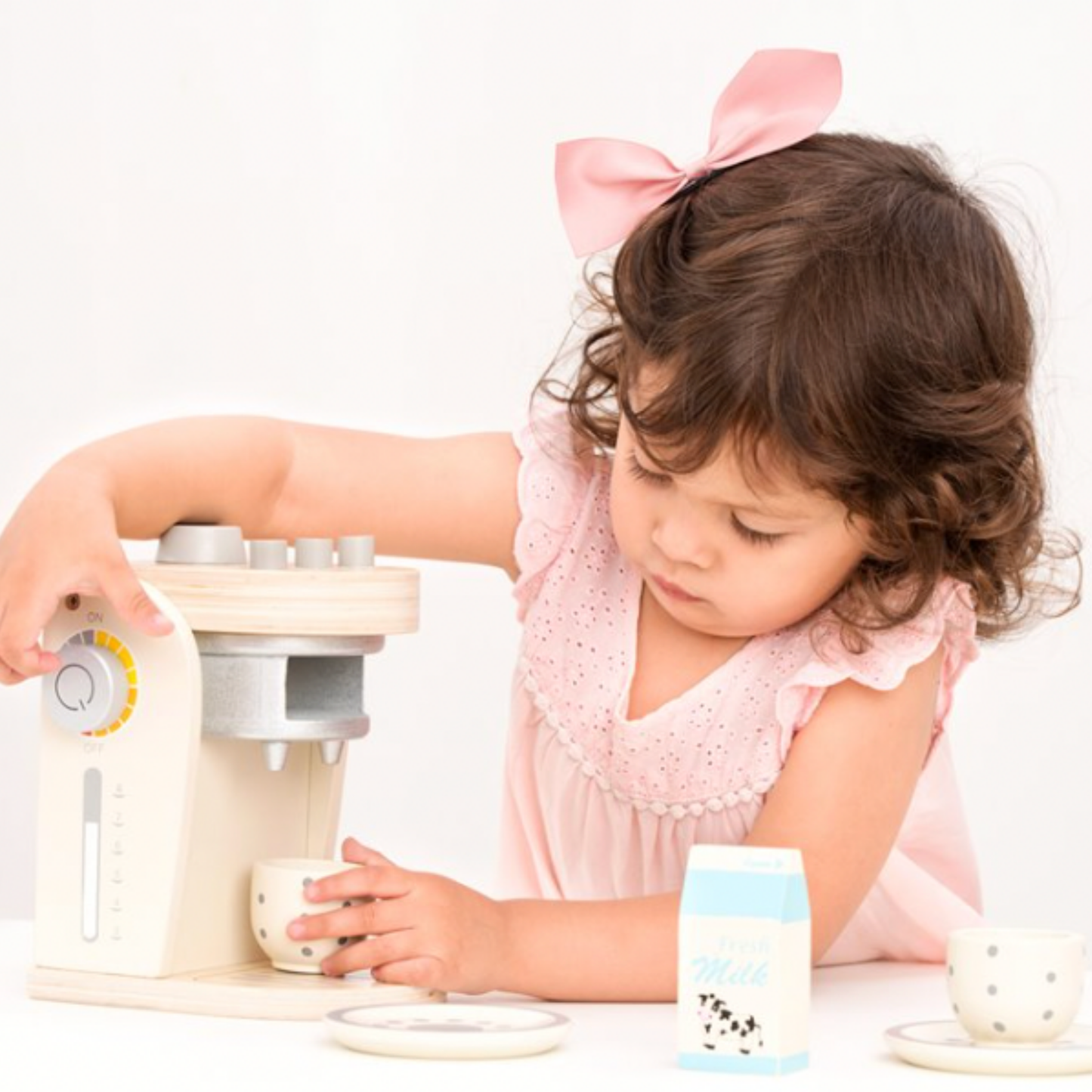 little girl playing with New Classic Toys wooden coffee machine on countertop