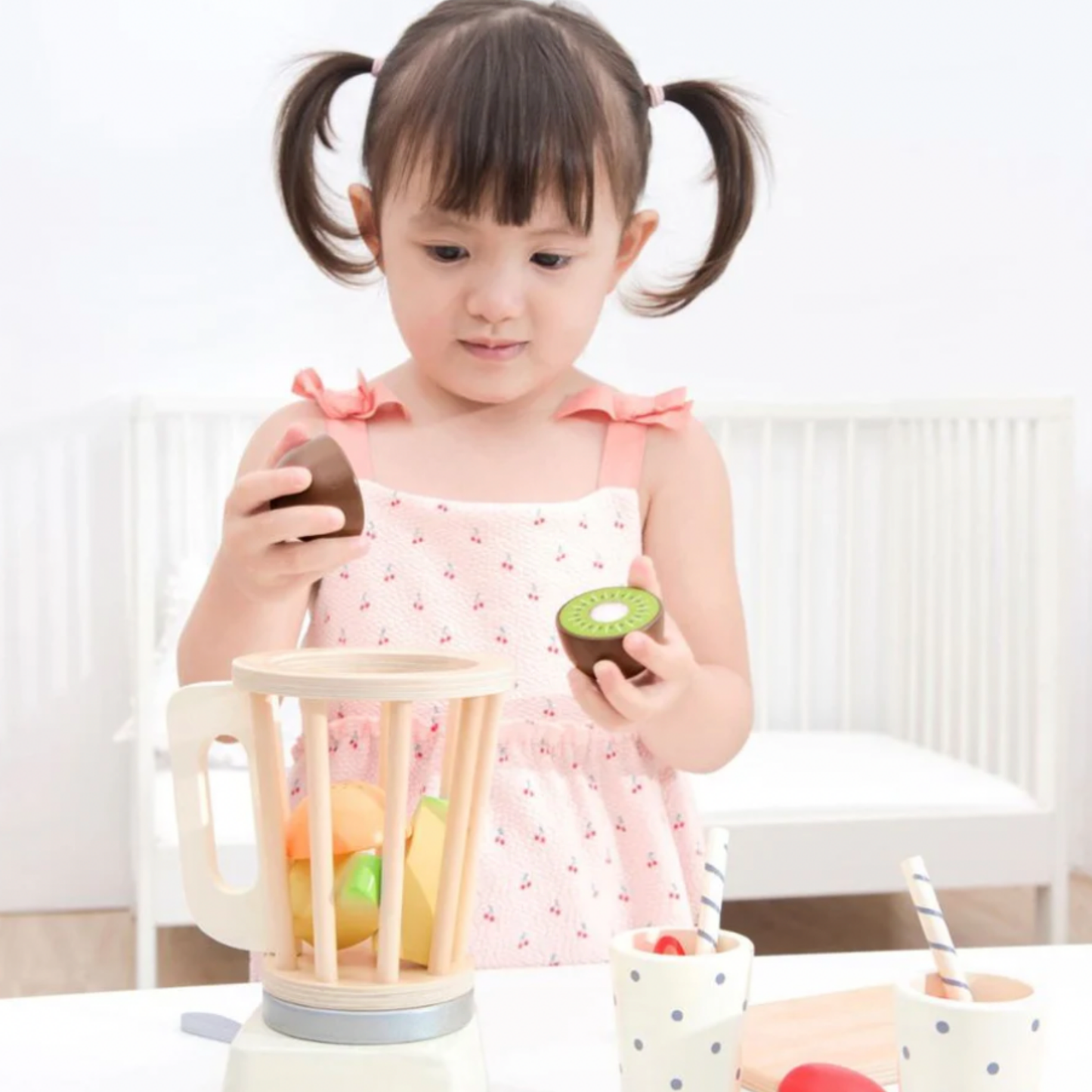 Little girl playing with New Classic Toys wooden blender set in bedroon