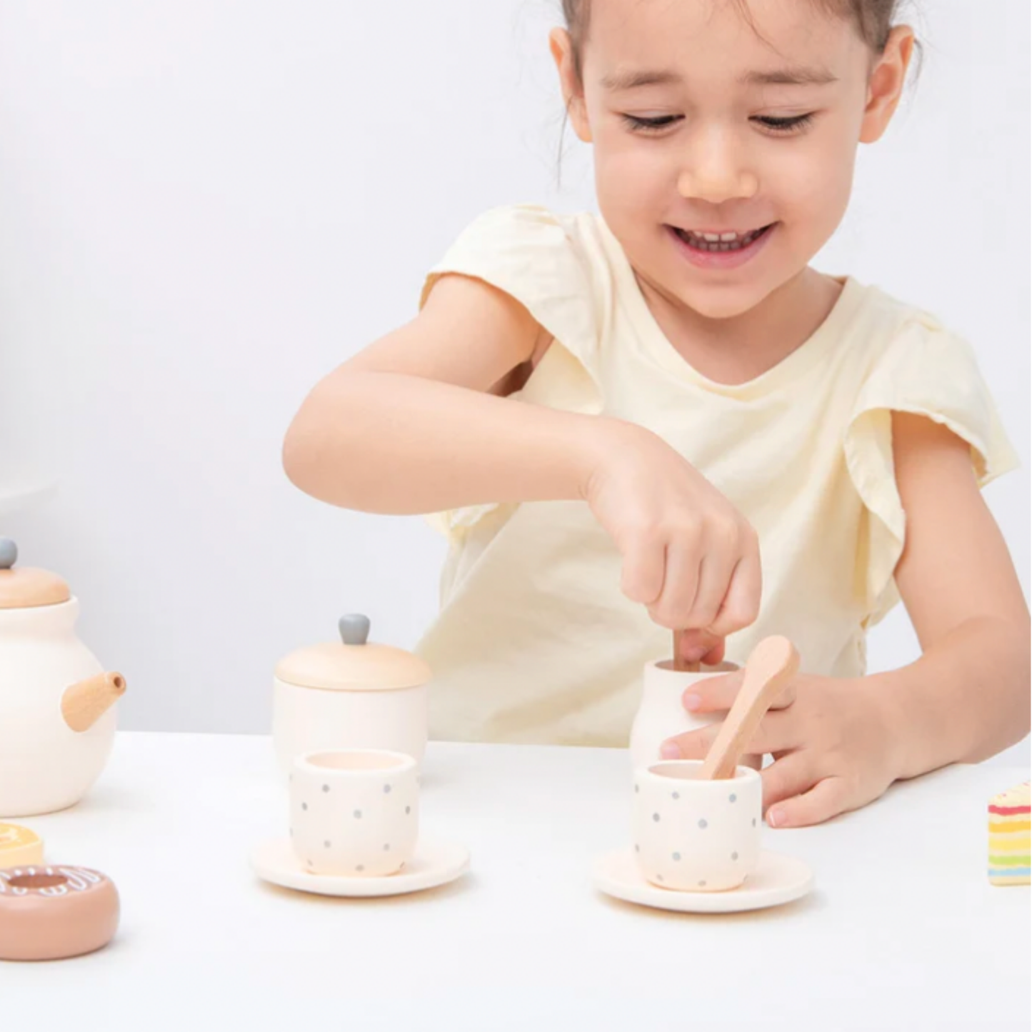 Little girl playing with New Classic Toys wooden tea set