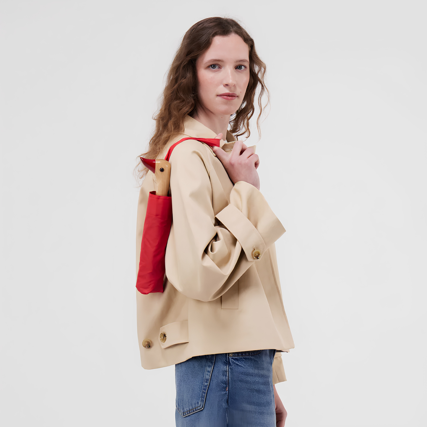 A woman with the kept Original Duckhead Duck Umbrella Compact Red in her shoulder through the handle strap, umbrella is from sustainable materials.