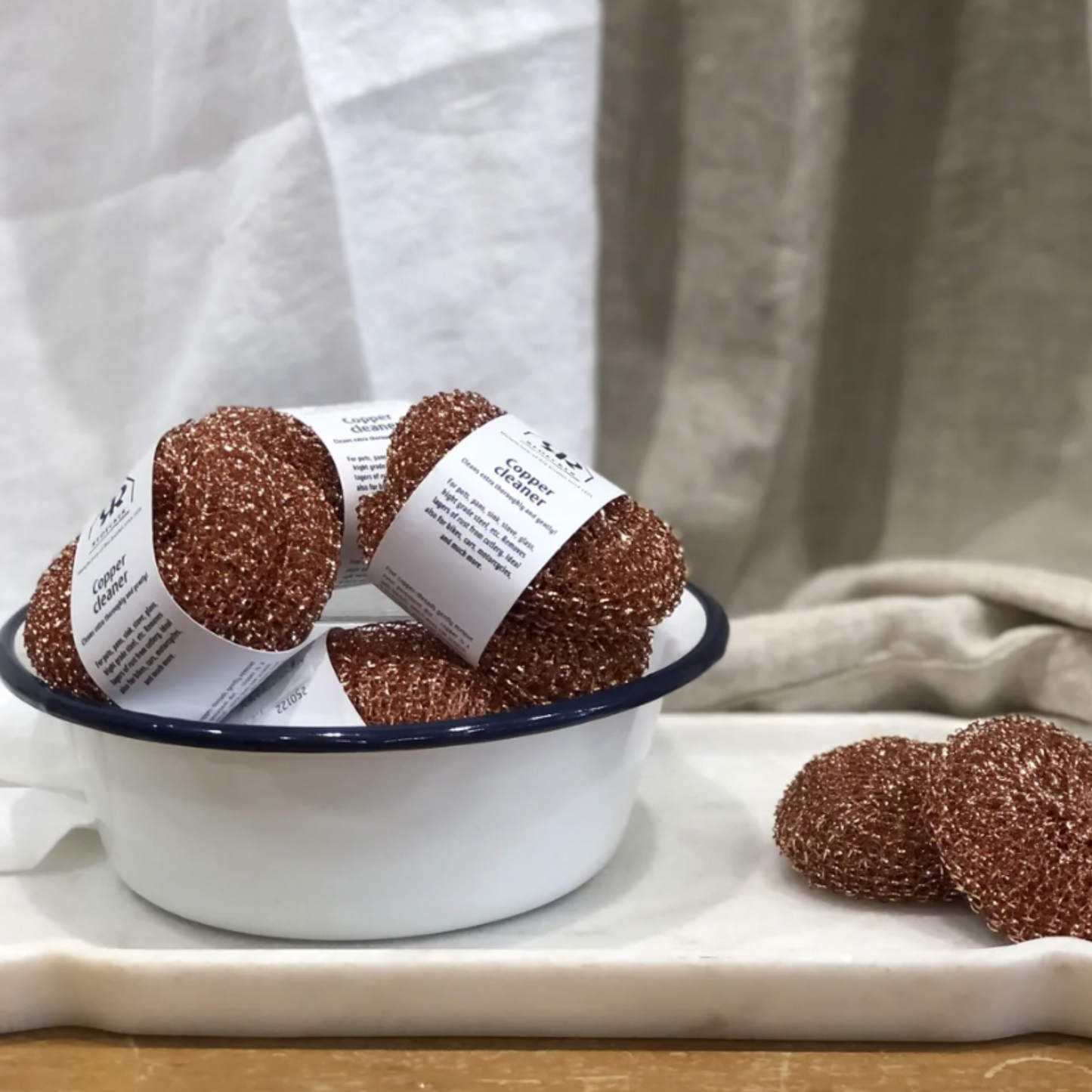 Redecker copper scourers on display in bowl in front of drapped linen