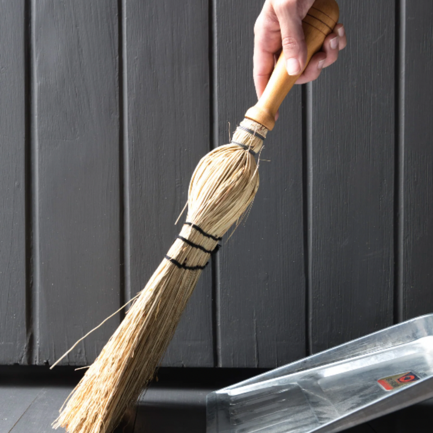 Woman using Redecker brush stitched with beech wood handle outside with dustpan