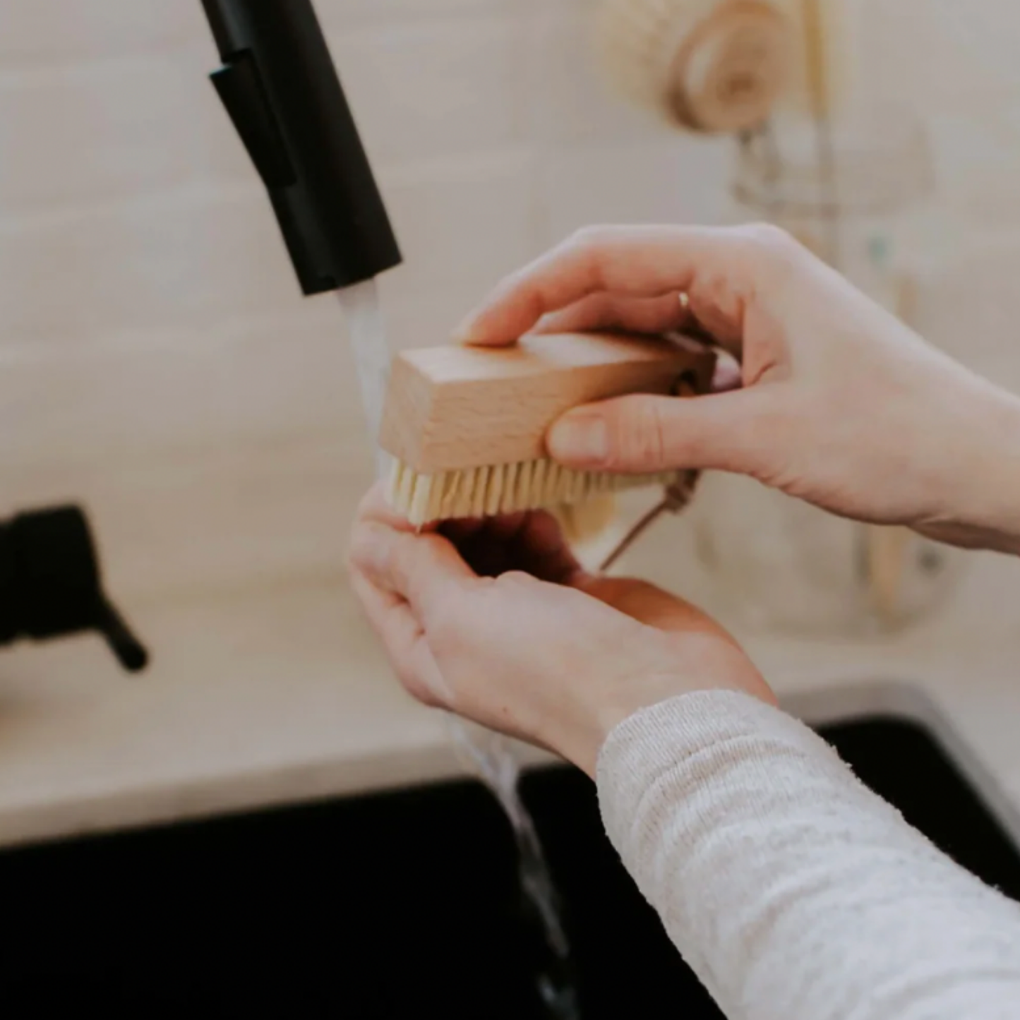 Woman using Redecker nail brush with leather strap at sink in kitchen