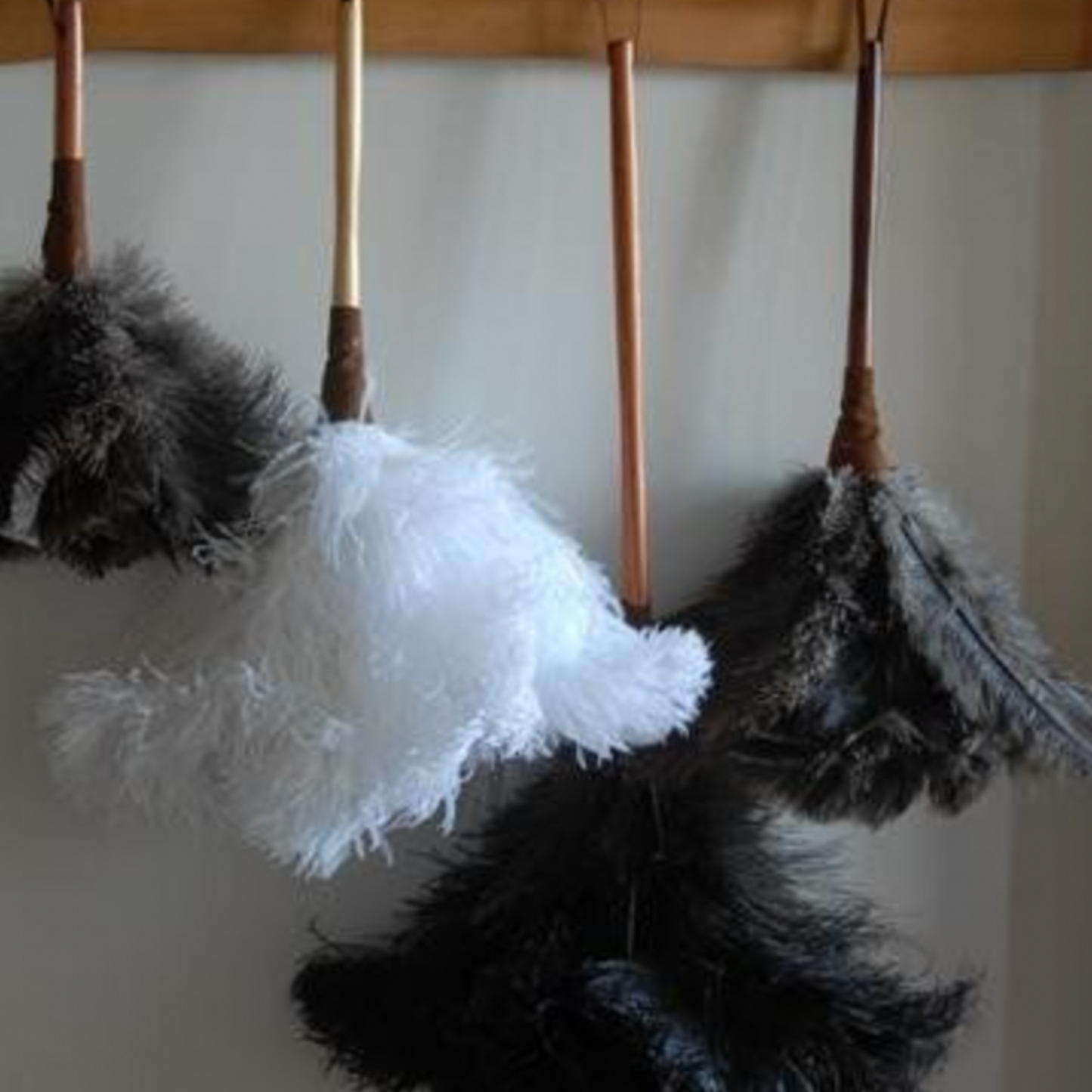 Assorted Redecker feather dusters hanging on wooden coat rack