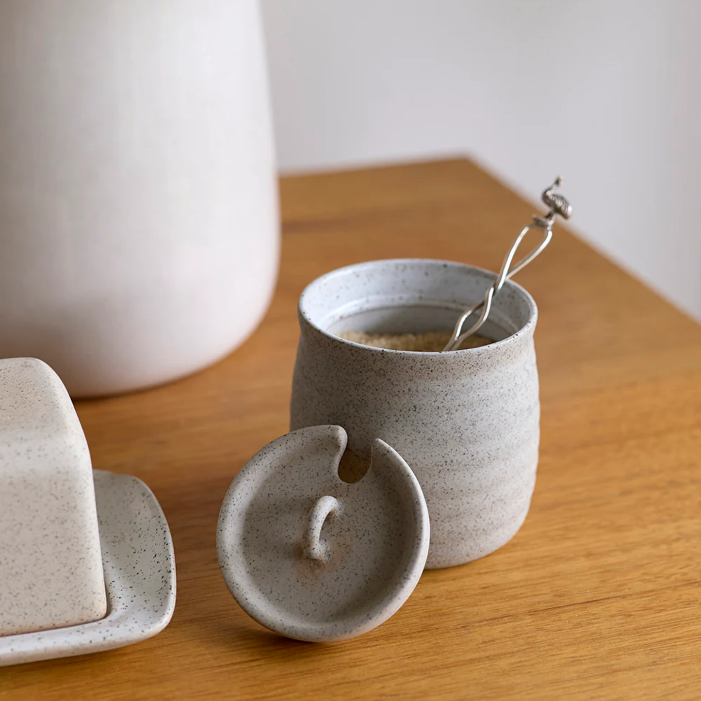 Robert Gordon sugar bowl with lid resting on side with spoon in bowl on display on wooden table