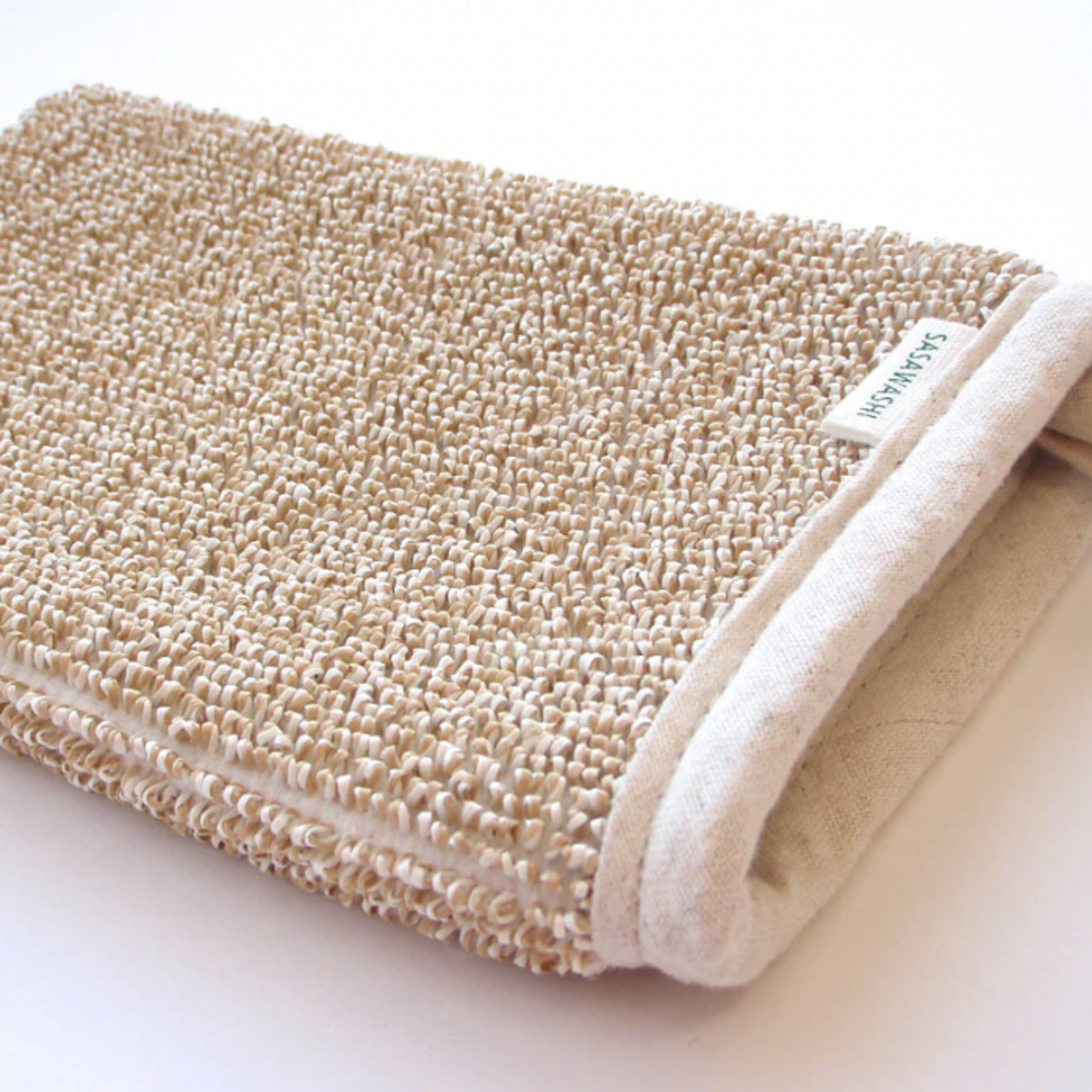 Angled view of the Sasawashi deep exfoliation mitten on countertop
