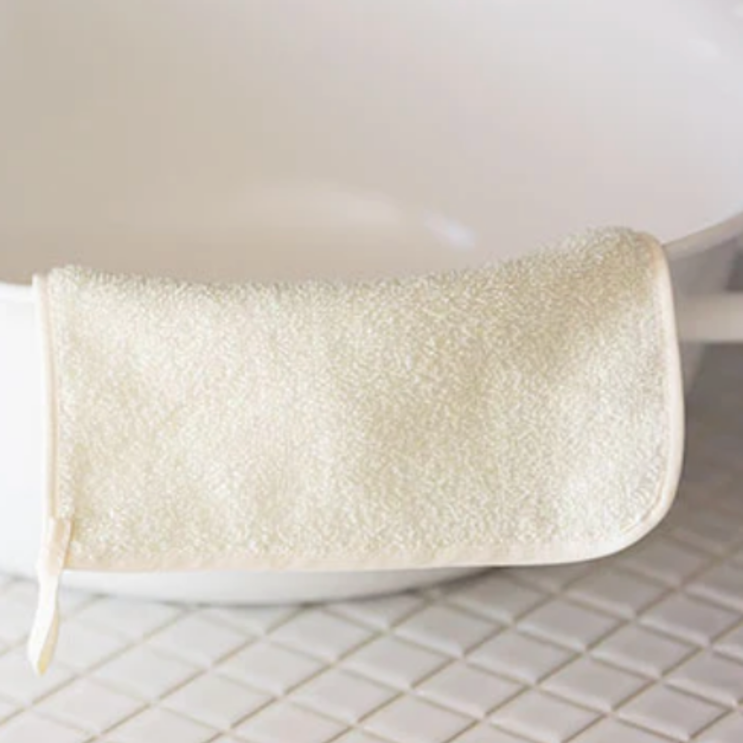 Sasawashi face scrub towel hanging over side of bathtub