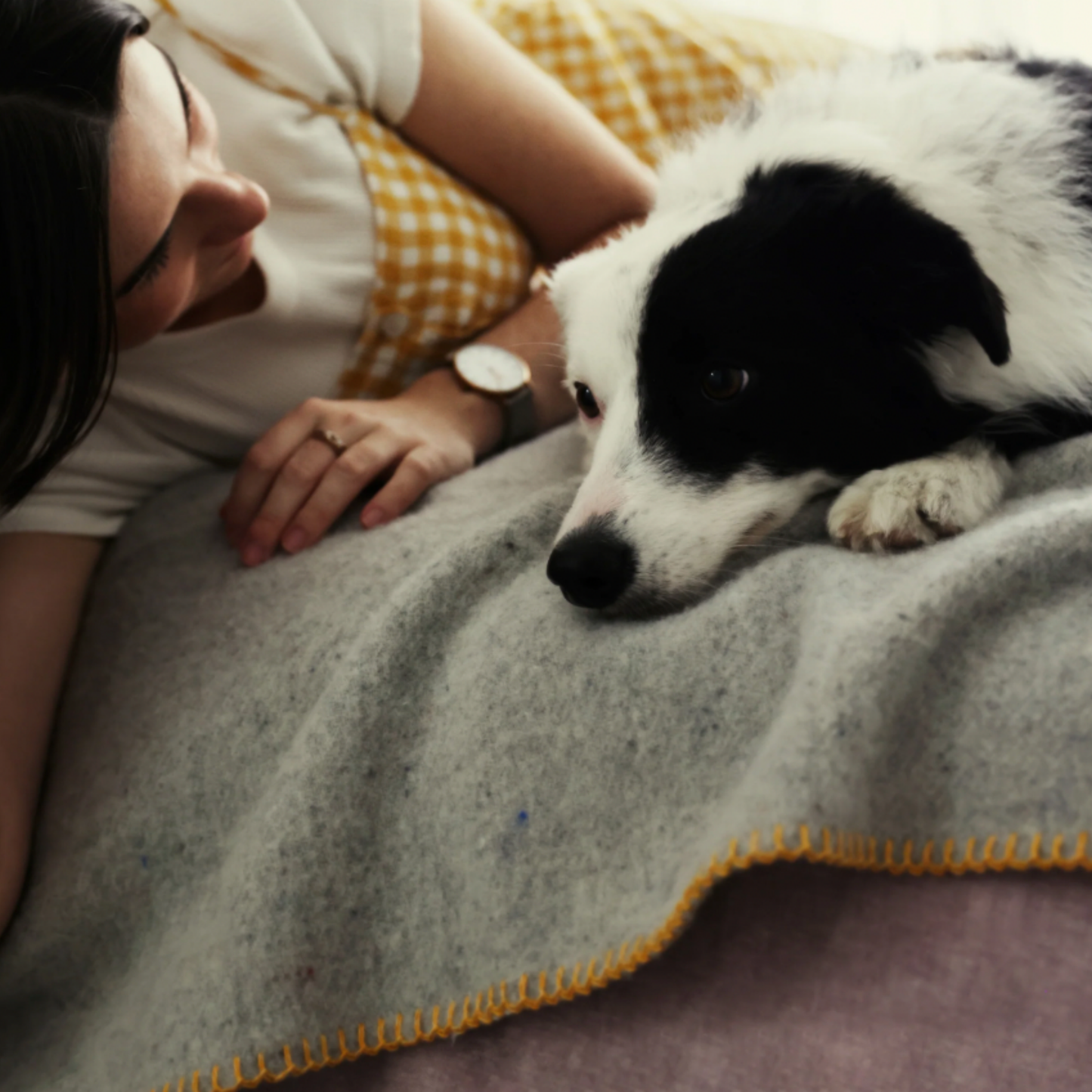 Woman lying down with dog on pet blanket close up