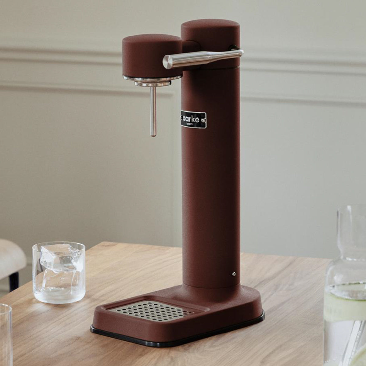 Stylish sparkling water maker designed by Aarke in Sweden showing the matte burgundy finish and displayed on kitchen surface