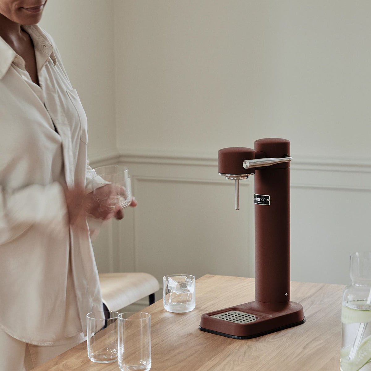 Stylish sparkling water maker designed by Aarke in Sweden showing the matte burgindy finish in use in kitchen