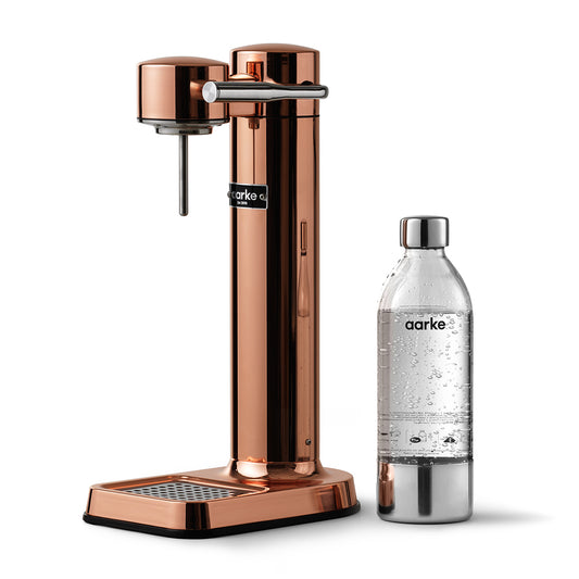 Stylish sparkling water maker designed by Aarke in Sweden showing the copper finish and the included 650ml PET water bottle