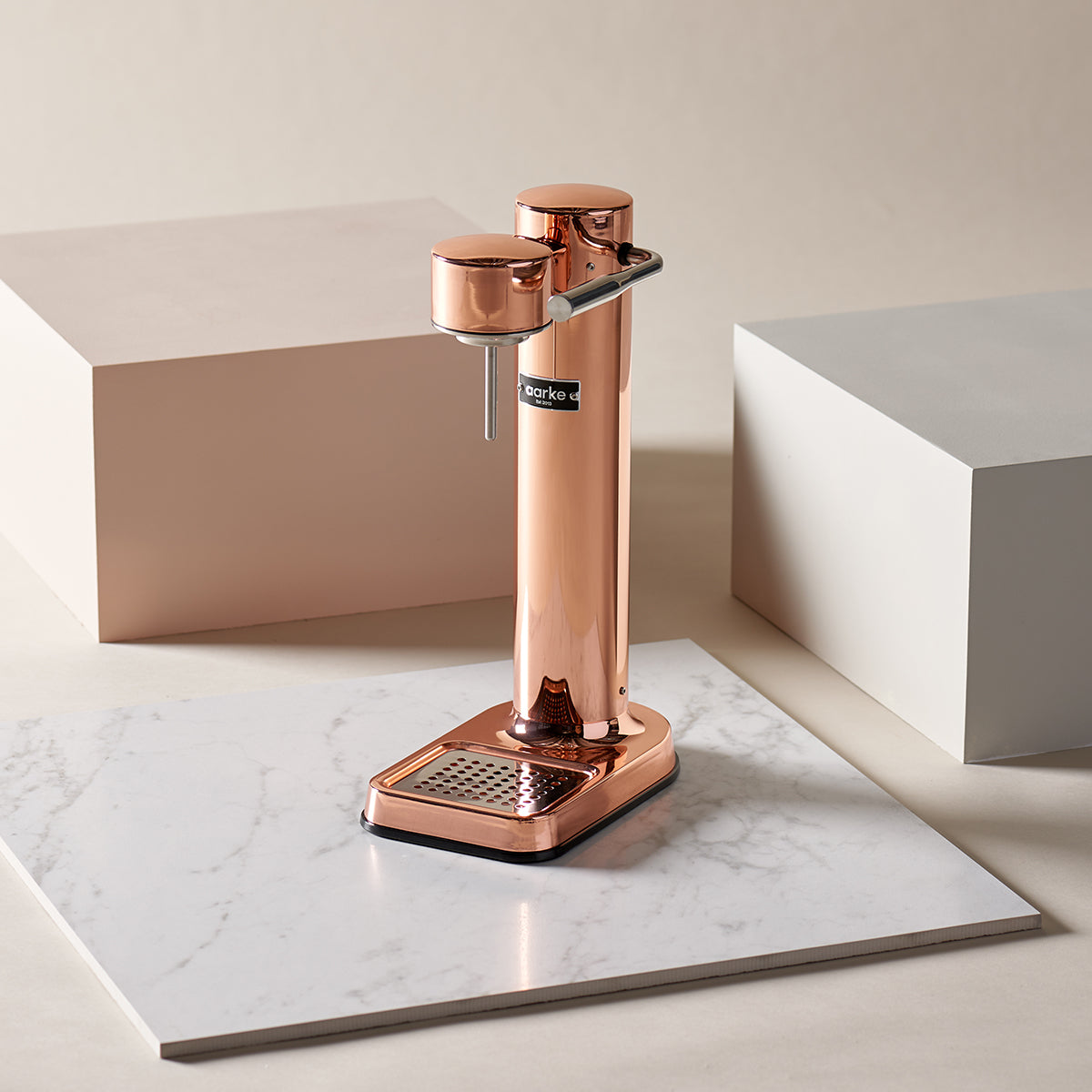 Stylish sparkling water maker designed by Aarke in Sweden showing the copper finish and displayed on marble surface