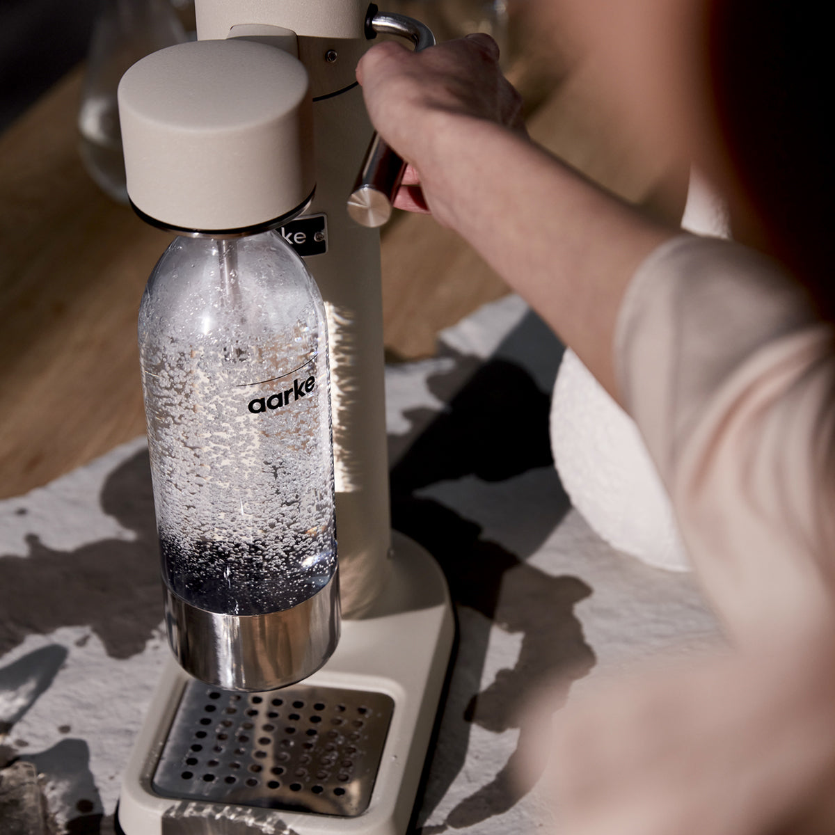 Close up of stylish sparkling water maker designed by Aarke in Sweden showing the sand finish and in use
