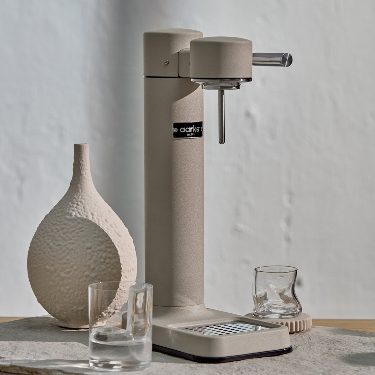Close up of stylish sparkling water maker designed by Aarke in Sweden showing the sand finish and displayed on the kitchen bench
