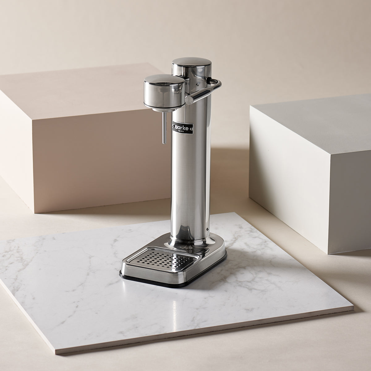 Stylish sparkling water maker designed by Aarke in Sweden showing the stainless steel finish and displayed on marble surface