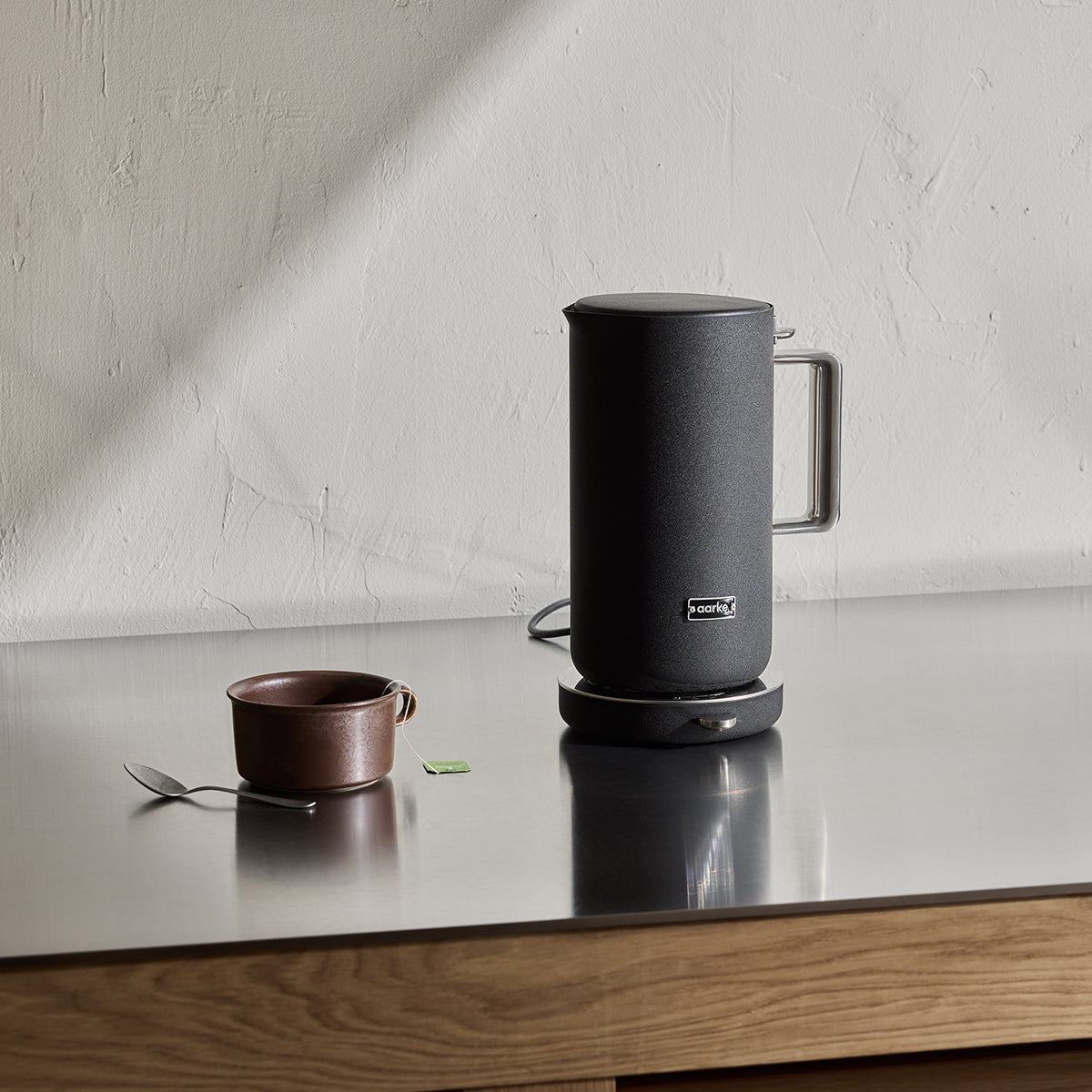 Stylish modern kettle made from stainless steel and designed in Sweden by Aarke with matte black displayed on kitchen bench