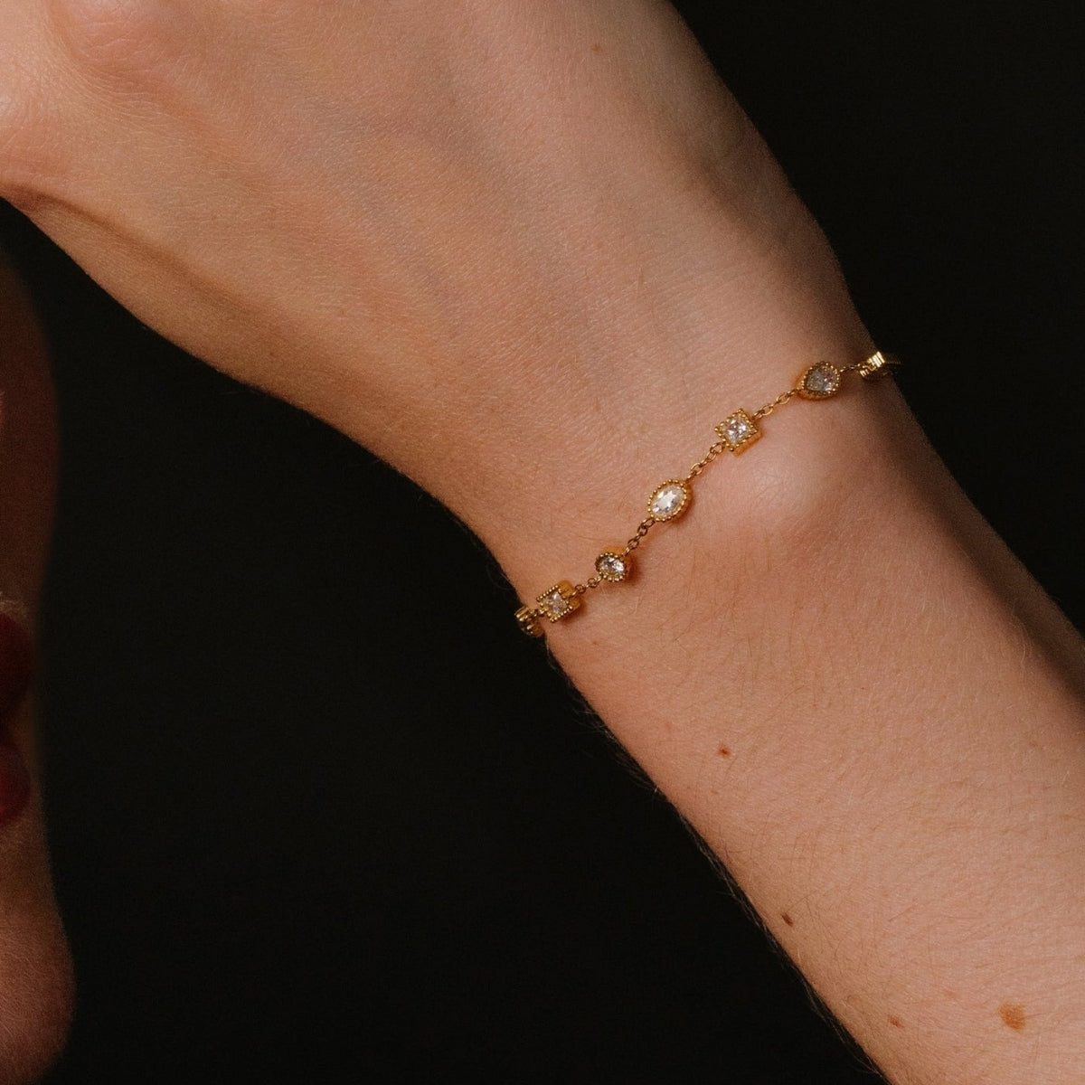 Showing the square and circle stations of the bracelet from AEC Paris Nila bracelet - gold multi-stone station bracelet in 14k gold-plated stainless steel, polished gold colour, durable hypoallergenic material featuring sparkling white cubic zirconia stones.