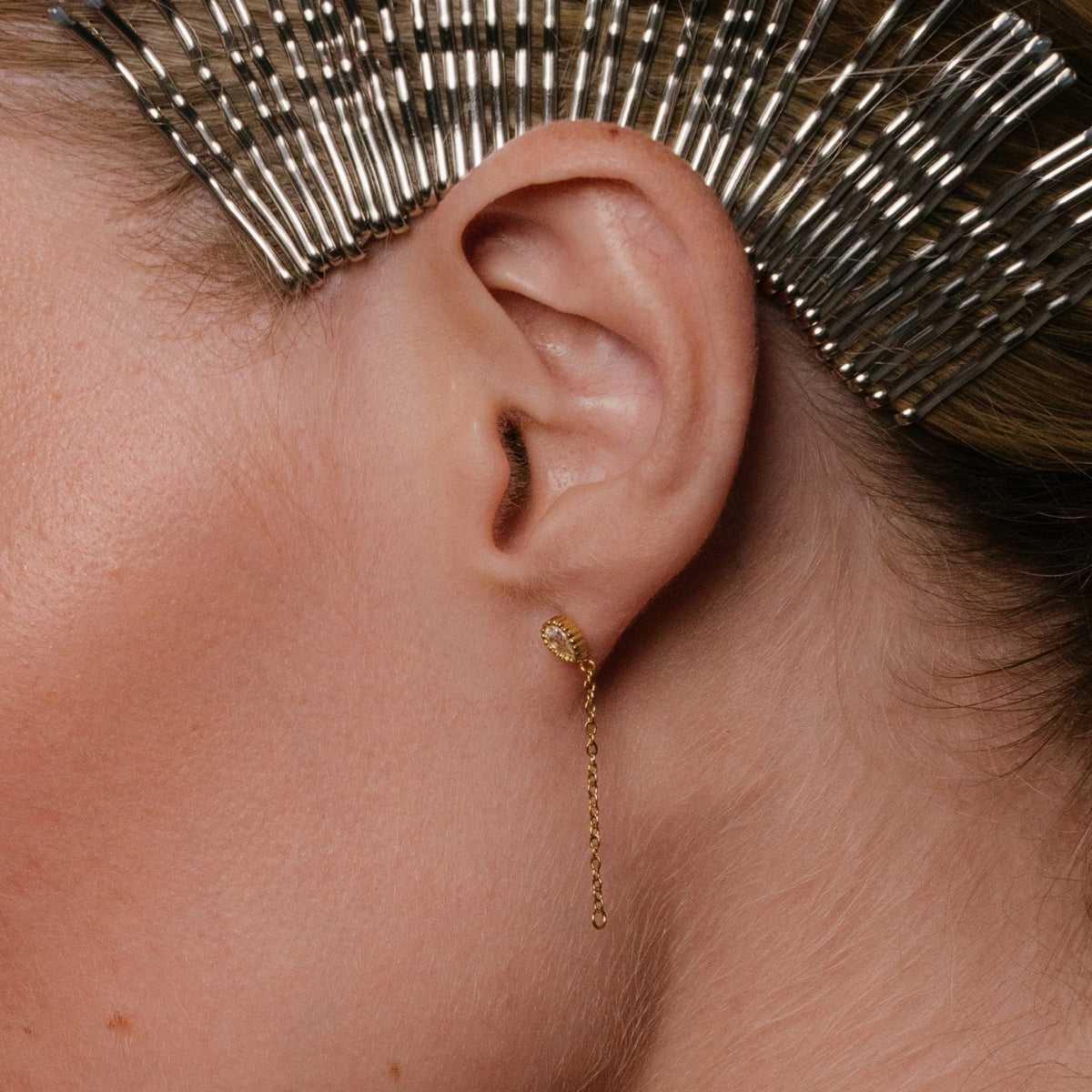 close up of woman wearing AEC Paris bala teardrop white-zirconium oxide earings with hundreds of hair clips on her hair