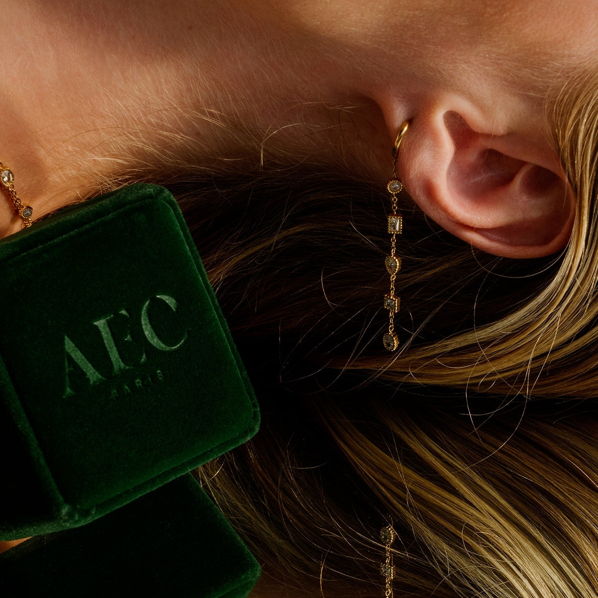 Showing the full view of AEC Paris Calie White Zirconium Oxide earrings shown from a woman wearing it - mini hoop earrings with multi-stone cubic zirconia dangle on 14k gold-plated stainless steel, hypoallergenic, durable, elegant everyday jewellery.