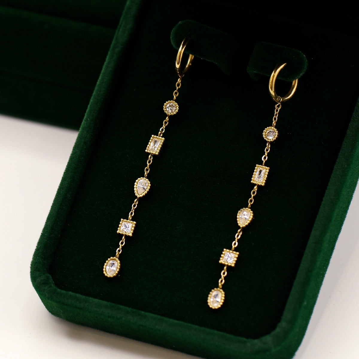 On its case AEC Paris Calie White Zirconium Oxide earrings - mini hoop earrings with multi-stone cubic zirconia dangle on 14k gold-plated stainless steel, hypoallergenic, durable, elegant everyday jewellery.